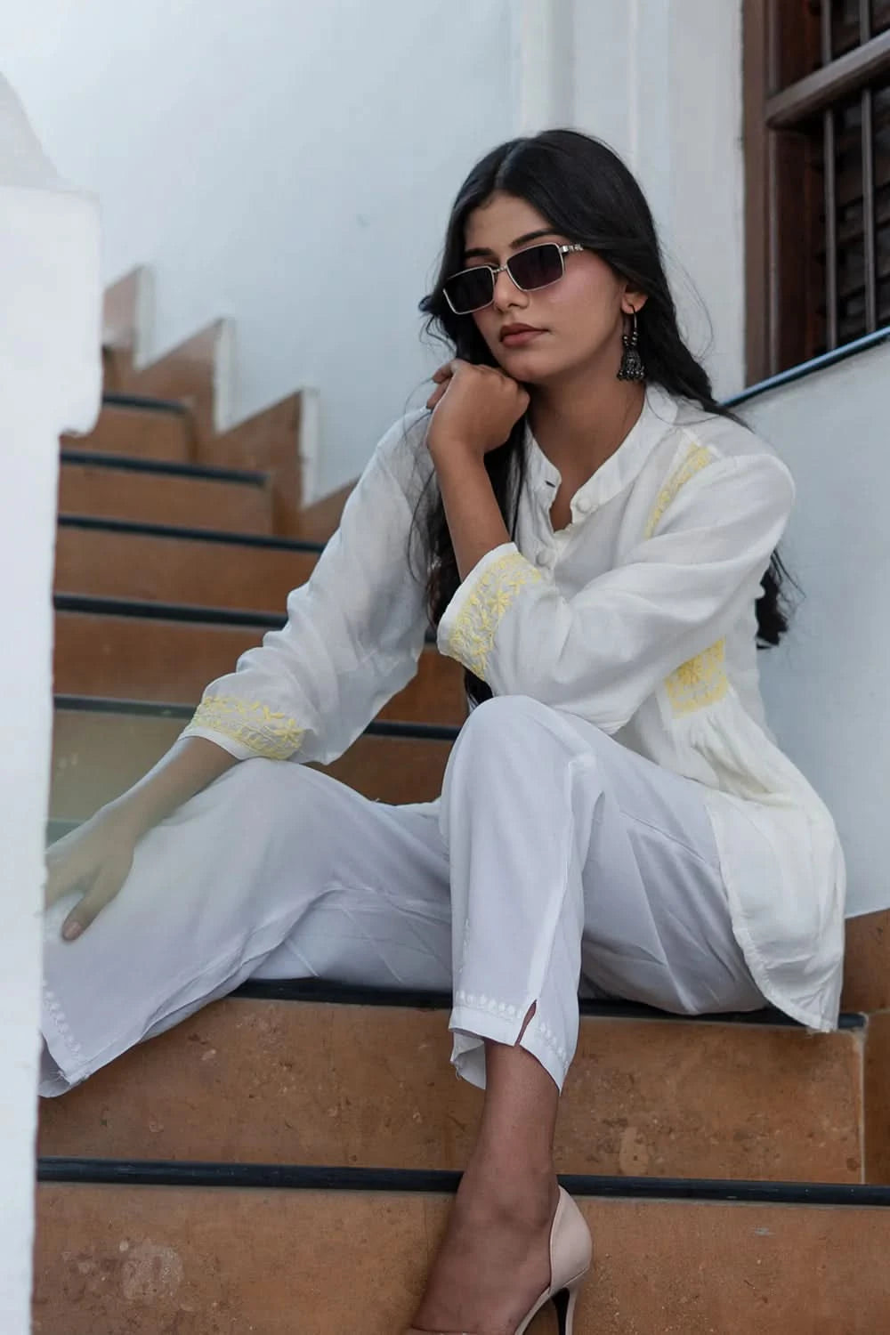 Woman in a white outfit sitting on steps outdoors