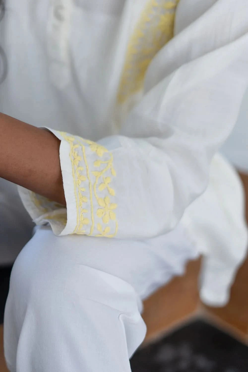 Close-up of a white garment with yellow embroidery on a blurred background