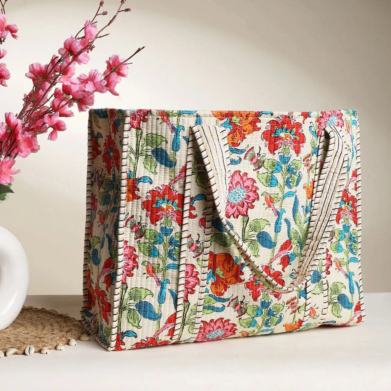 Colorful floral-patterned bag on a neutral background with pink flowers.
