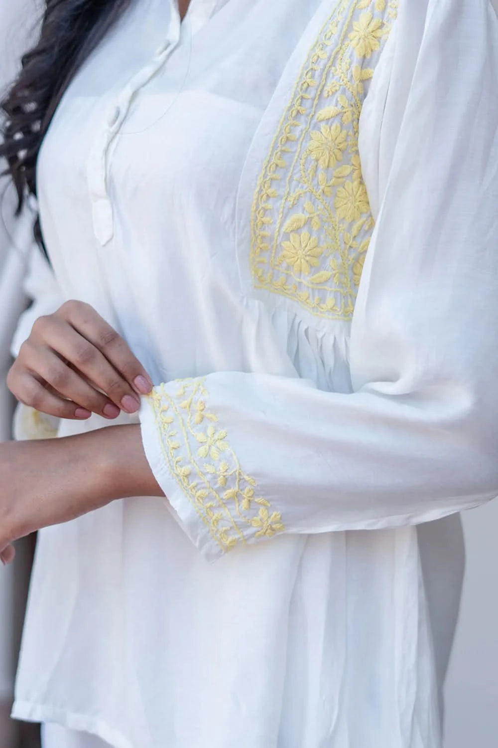 White blouse with yellow embroidery on a white background
