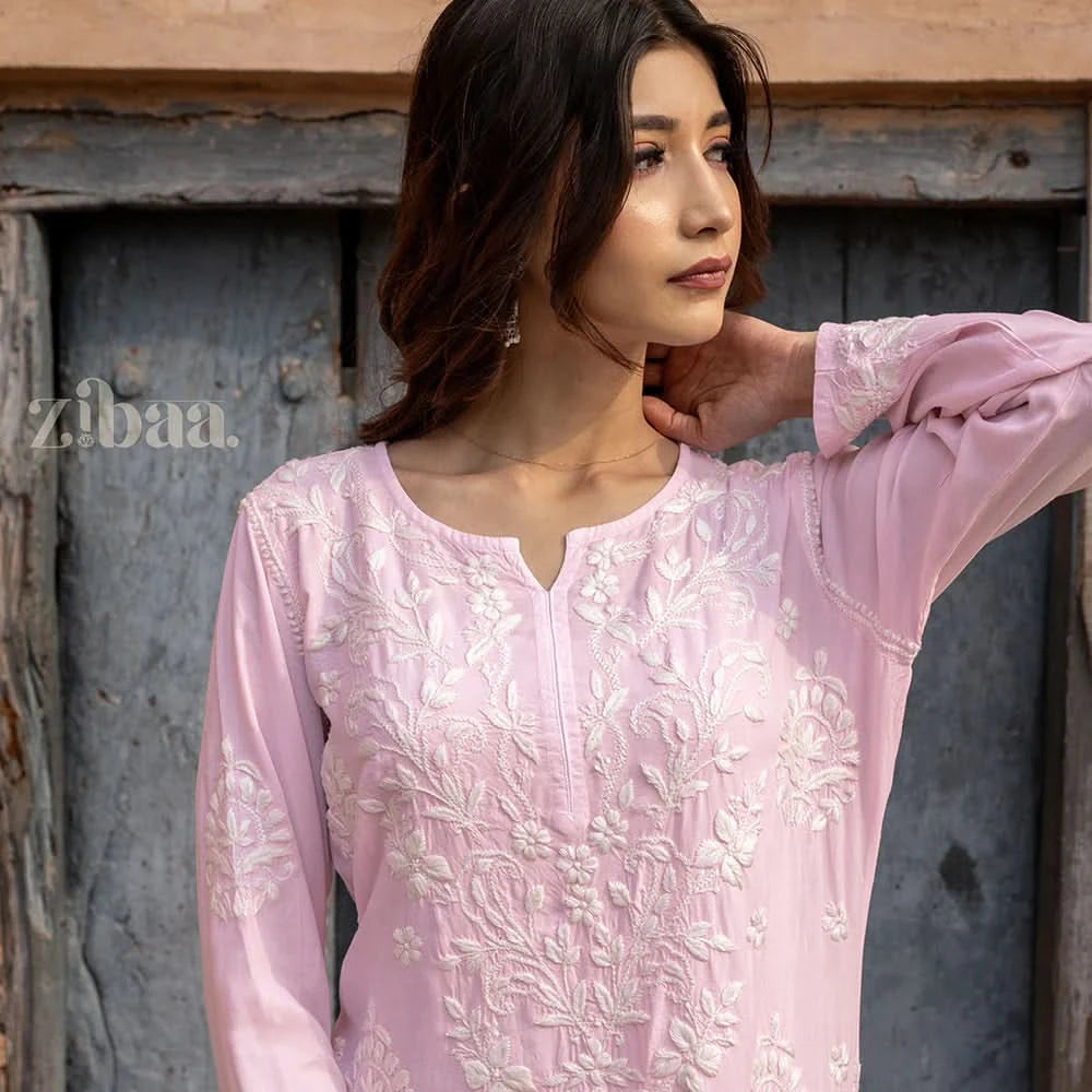 Woman wearing a pink embroidered top with a rustic background