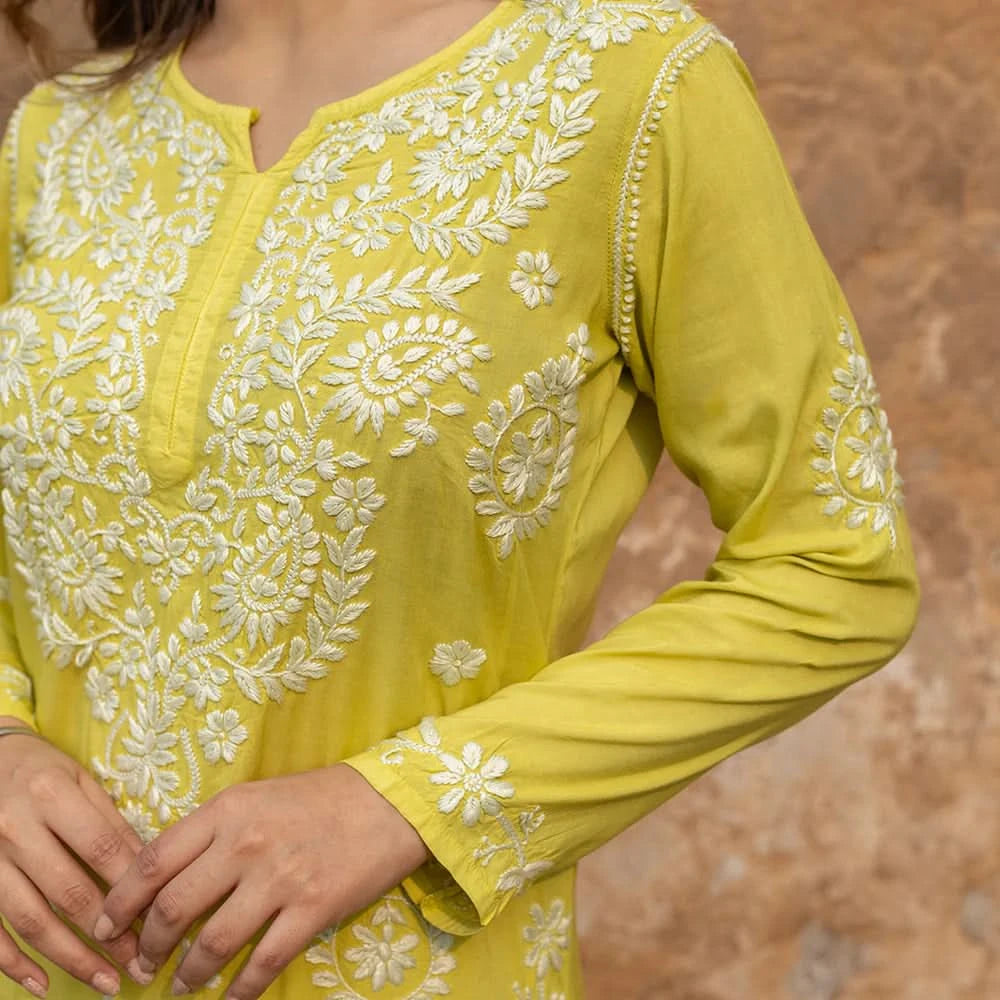 Yellow embroidered garment with white floral patterns on a blurred background