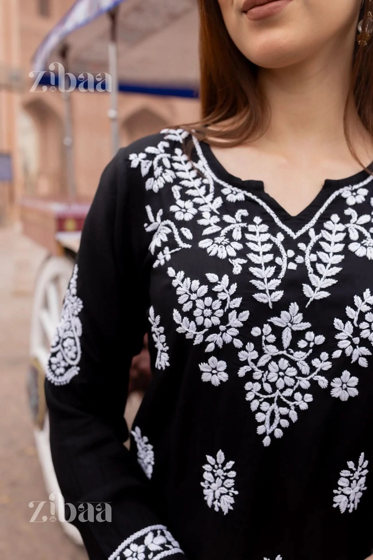 Close-up of black short chikankari kurti showing detailed floral embroidery.