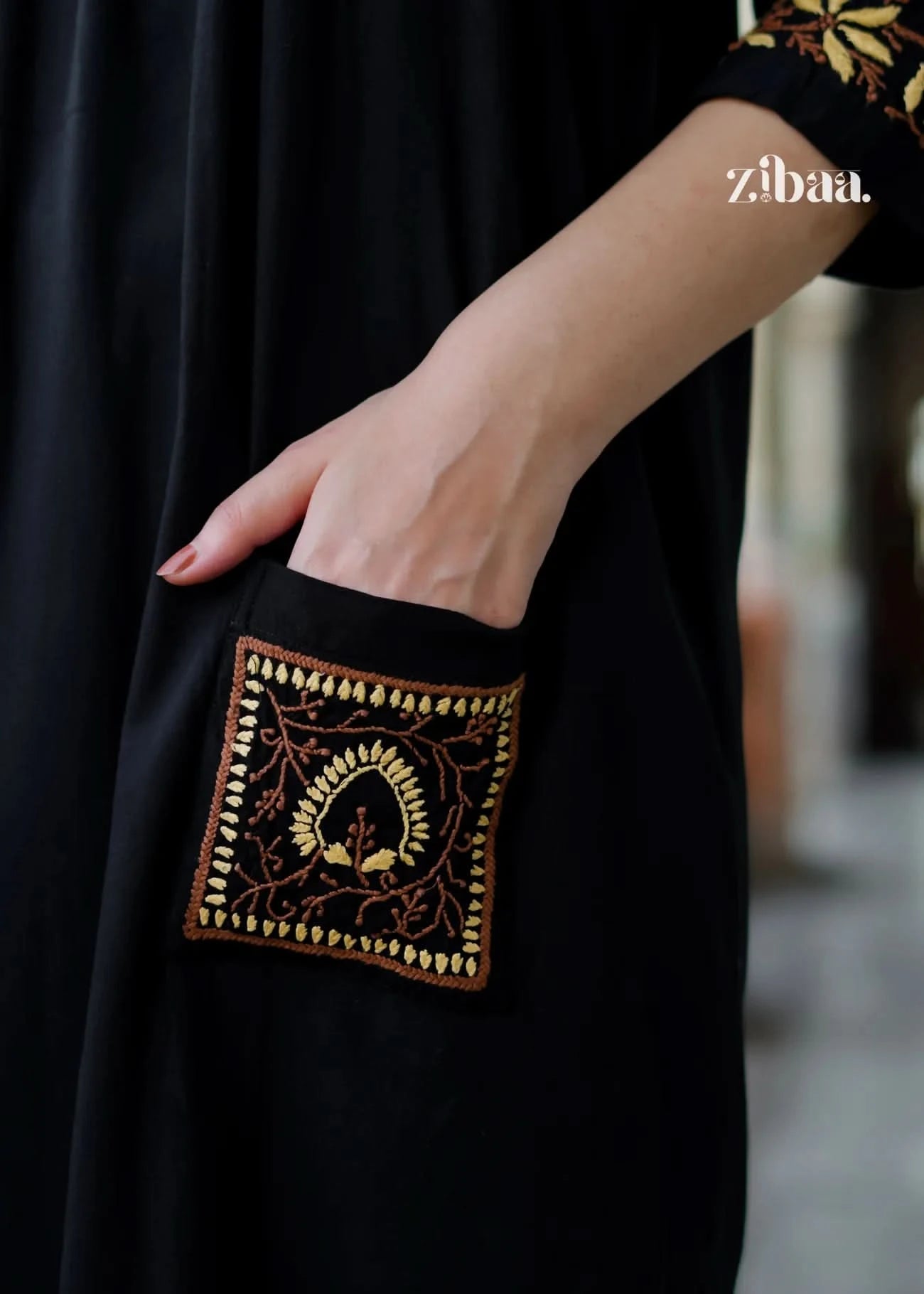 The intricate golden threadwork on the black chikankari kurti is captured up close, emphasizing the skill and precision involved.