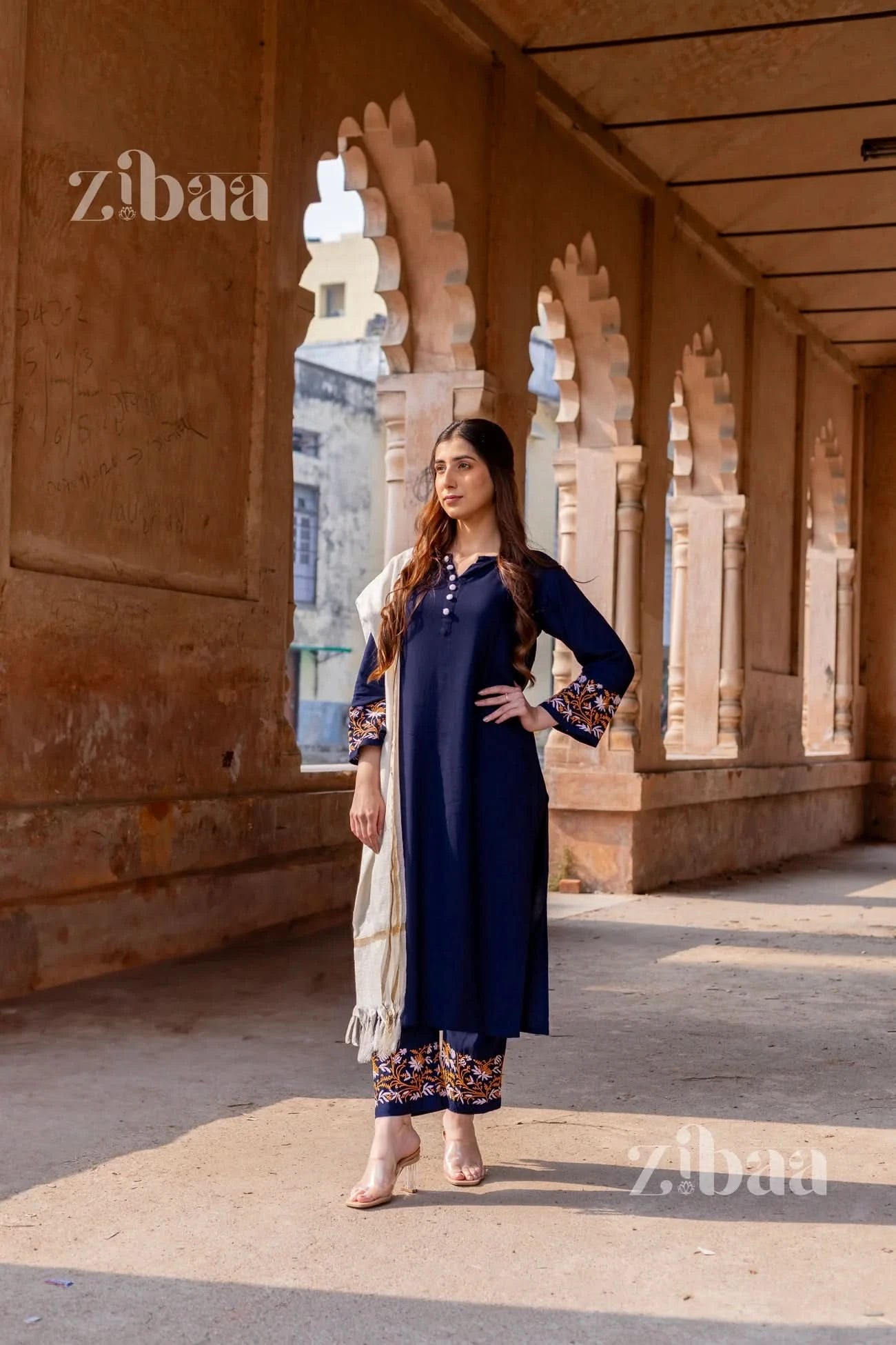 Model dressed in a blue chikankari kurta set featuring floral embroidery, paired with a white mulmul dupatta.