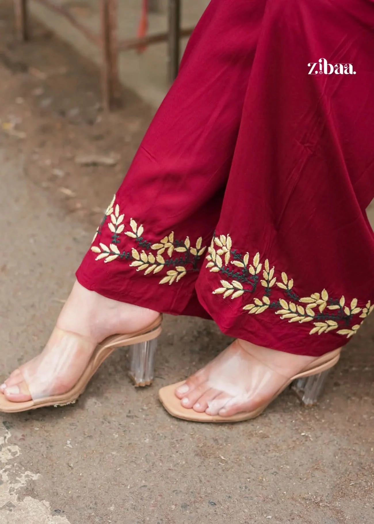 Detailed view of chikankari embroidery on burgundy pants.