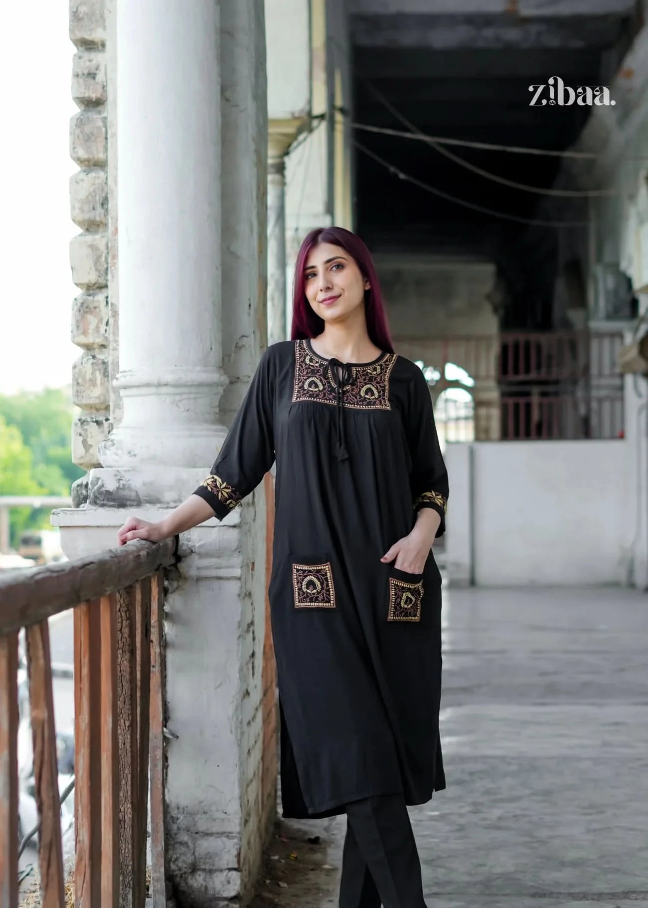 The model poses confidently in a black chikankari kurti, showcasing the intricate golden embroidery on the pockets, cuffs, and neckline.