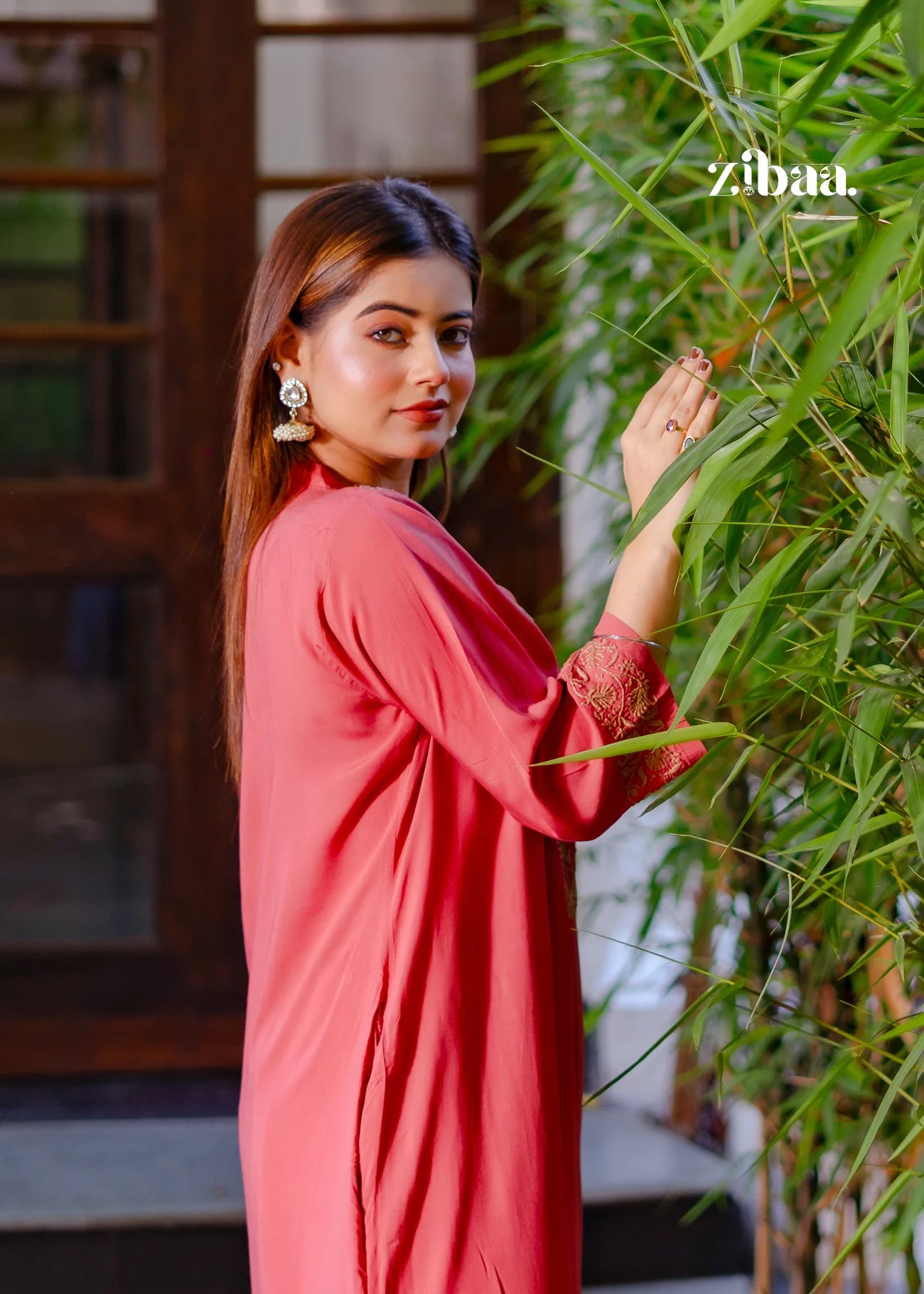 The model stands confidently, wearing a coral chikankari kurti that highlights the fine chikankari stitching.
