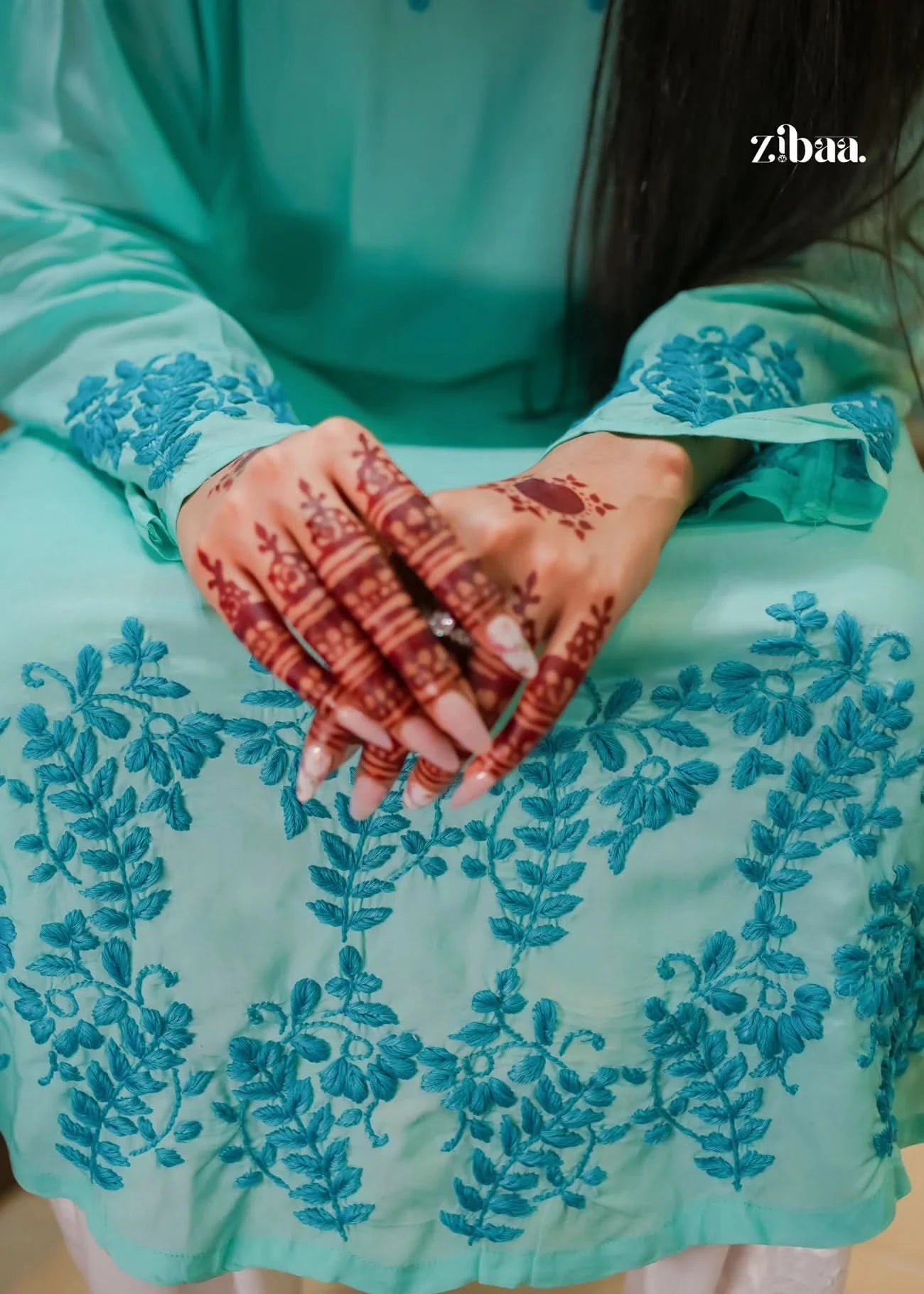 Model wearing a beautiful blue chikankari kurti with fine detailing. Her hands, adorned with henna and colorful designs, add a touch of tradition and grace.