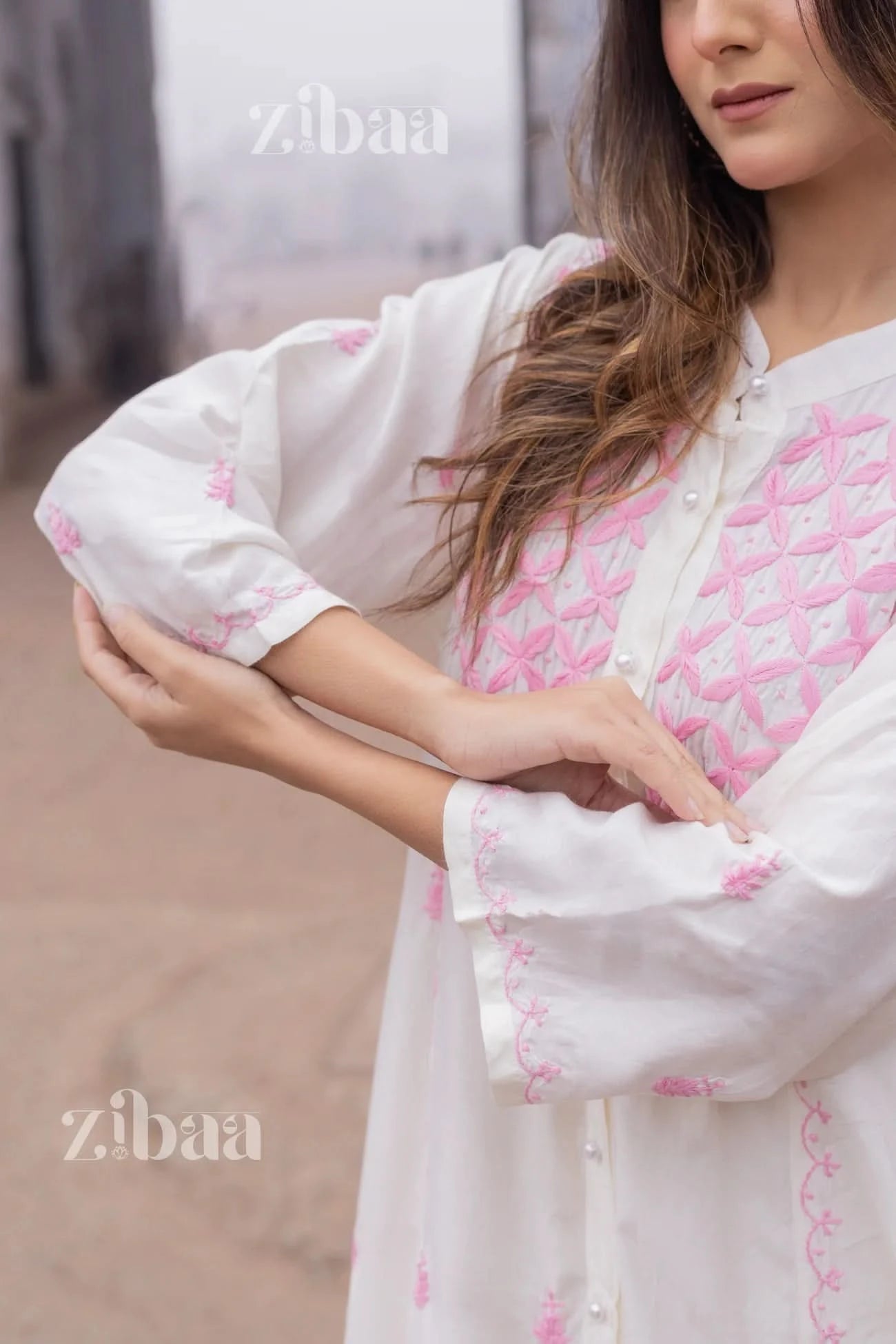 White chikankari kurta styled outdoors, with traditional fine stitching in pink threads clearly visible on the kurta.