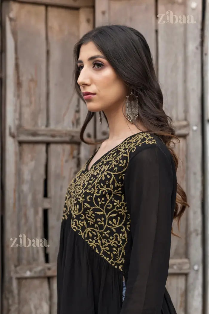 An aerial view of a black Chikankari Kurti, featuring gold embroidery. This was styled with jeans to portray elegance in a rustic outdoor setting.