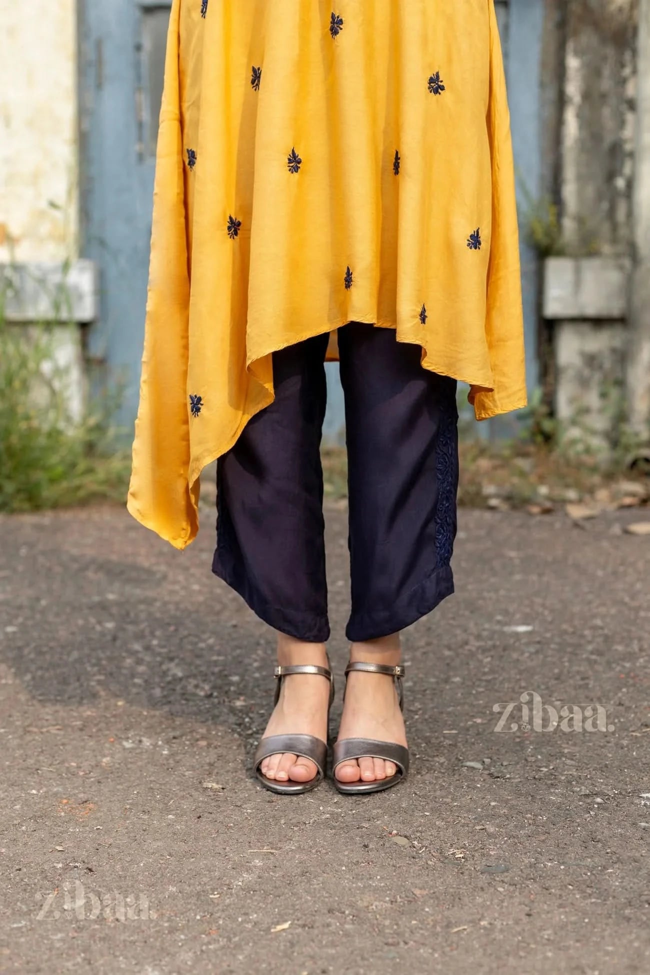 A close-up of navy Chikankari Palazzo pants paired with a mustard kurta, highlighting elegant embroidery and a stylish hemline.