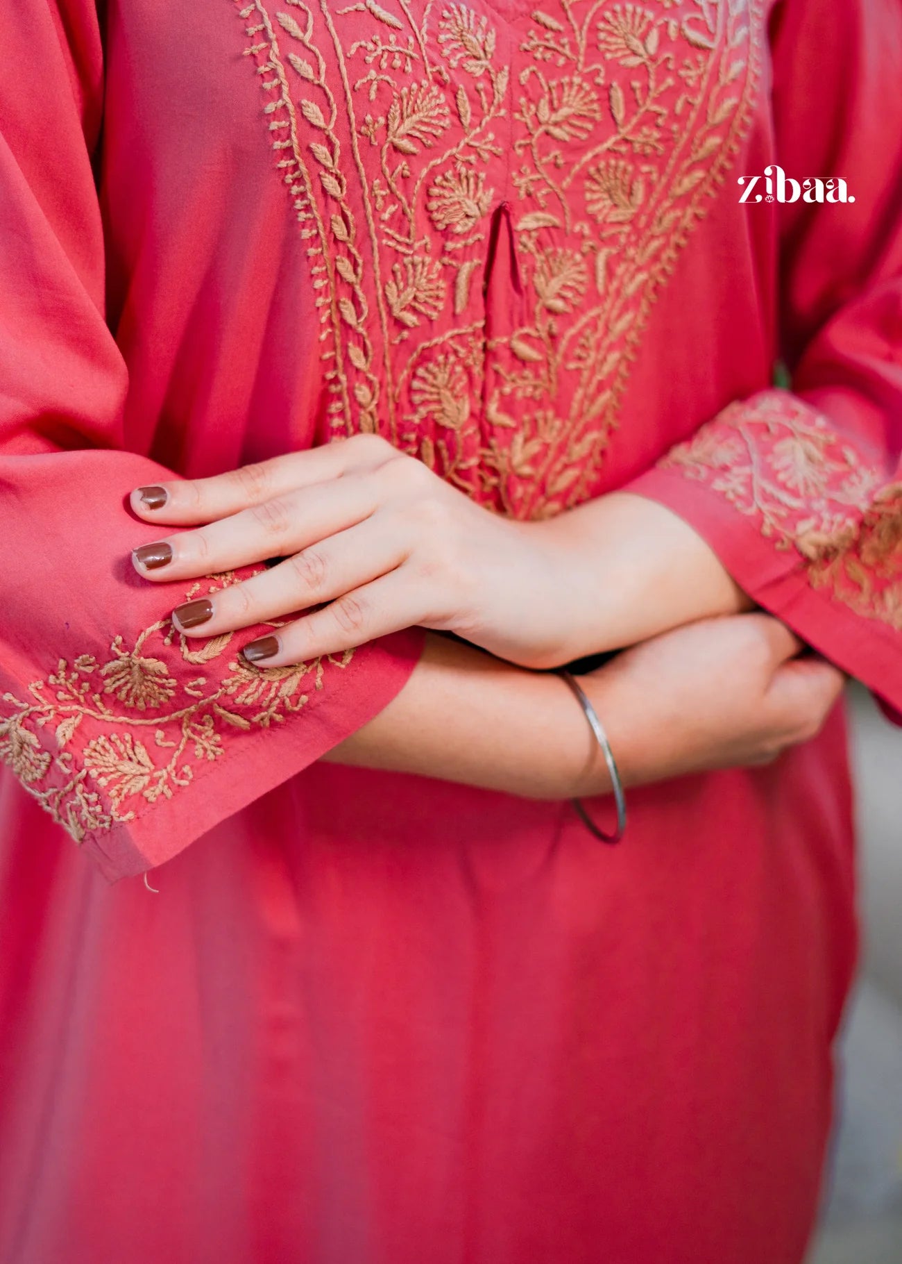 A close-up reveals the delicate golden embroidery threadwork on the coral chikankari kurti, highlighting the intricate craftsmanship and vibrant details.