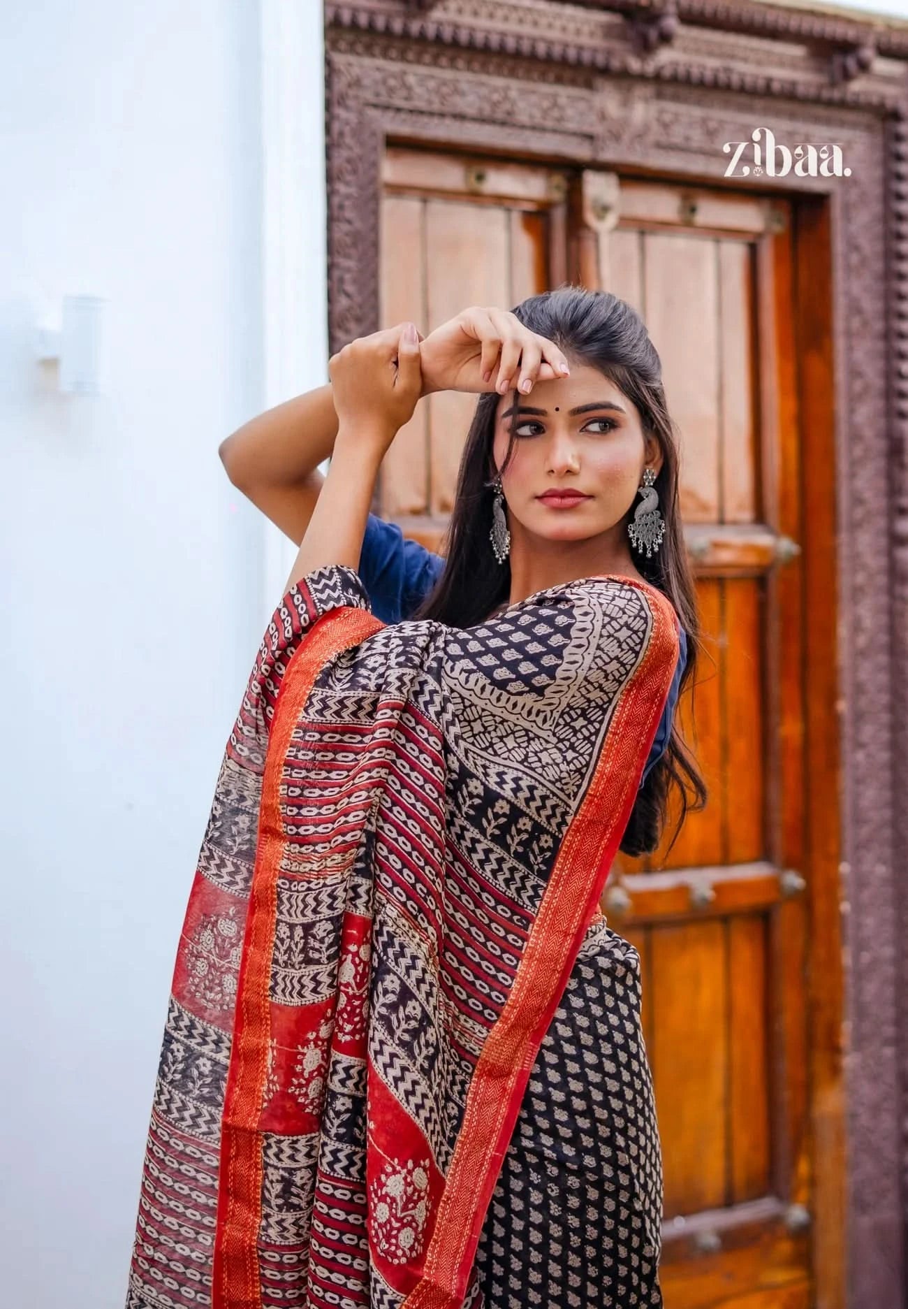 Woman wearing a patterned scarf with a wooden door in the background
