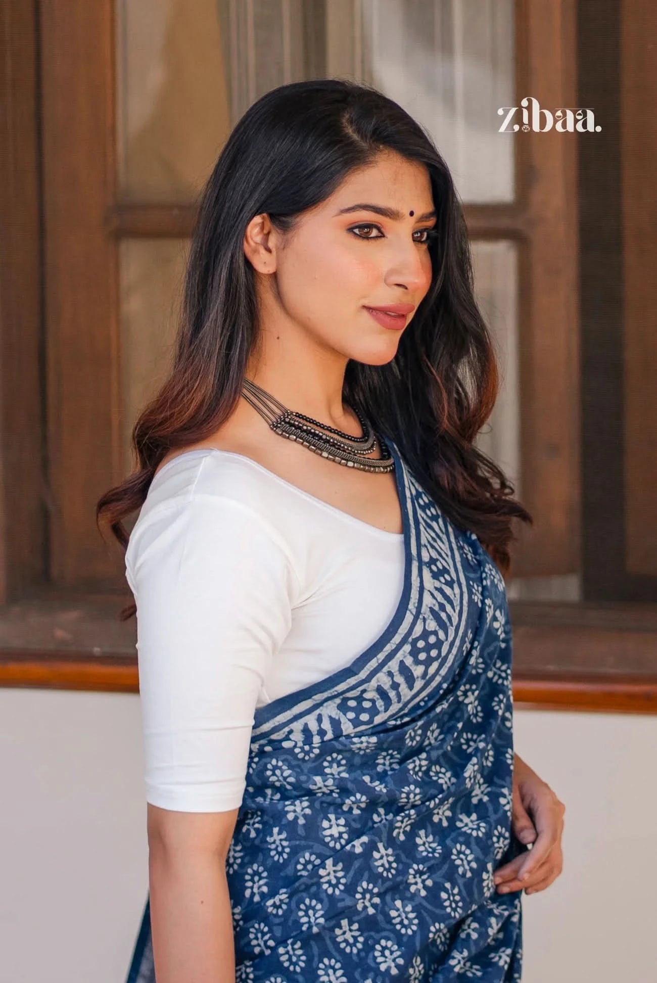 Woman wearing a blue and white saree with a blurred background