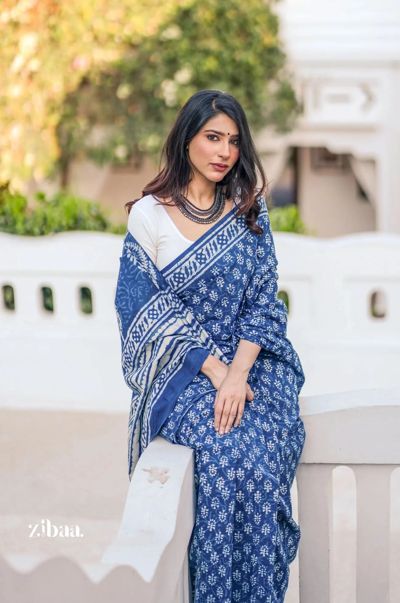 Woman wearing a blue saree with white patterns outdoors