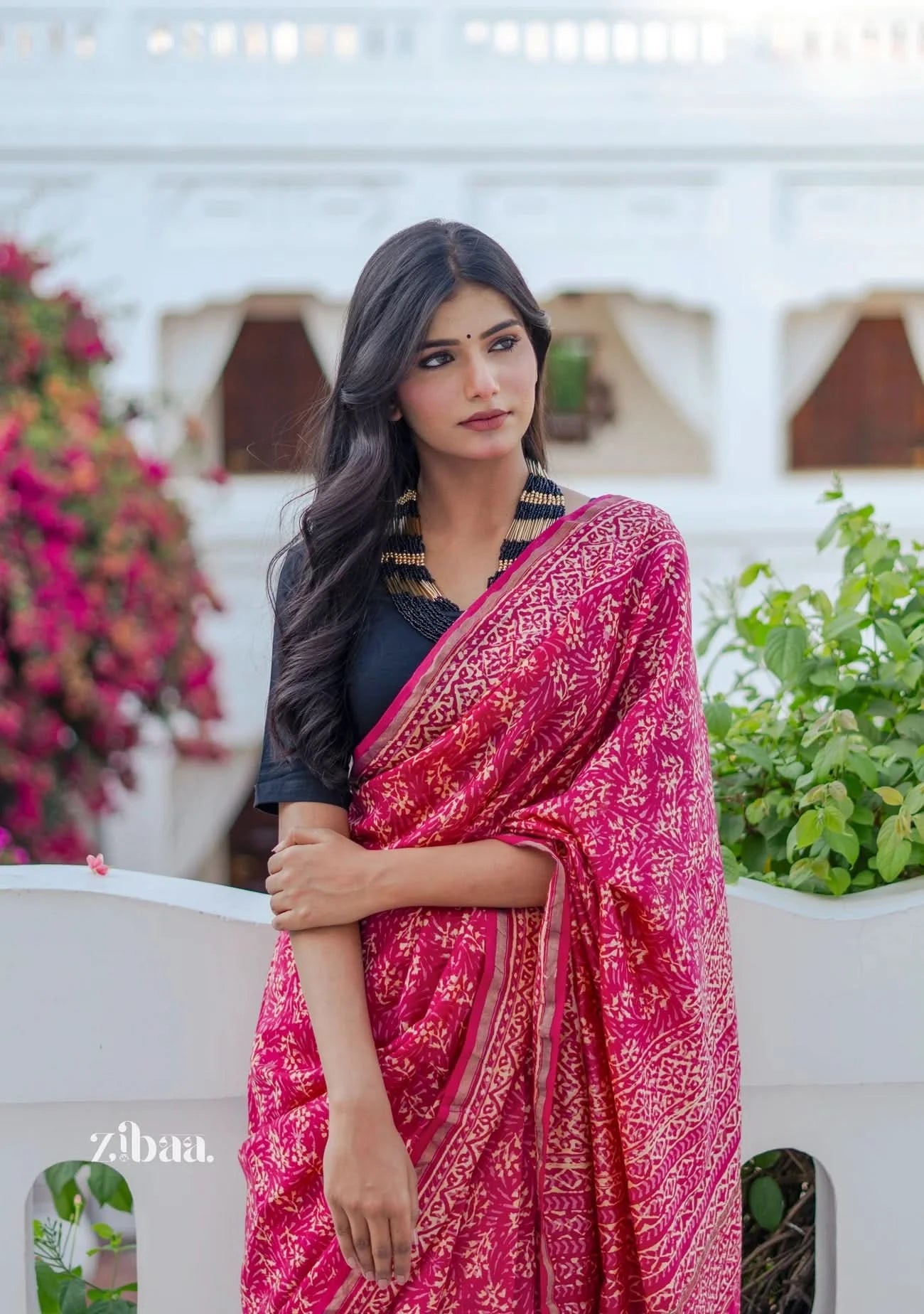 Woman wearing a pink saree with a black blouse in an outdoor setting