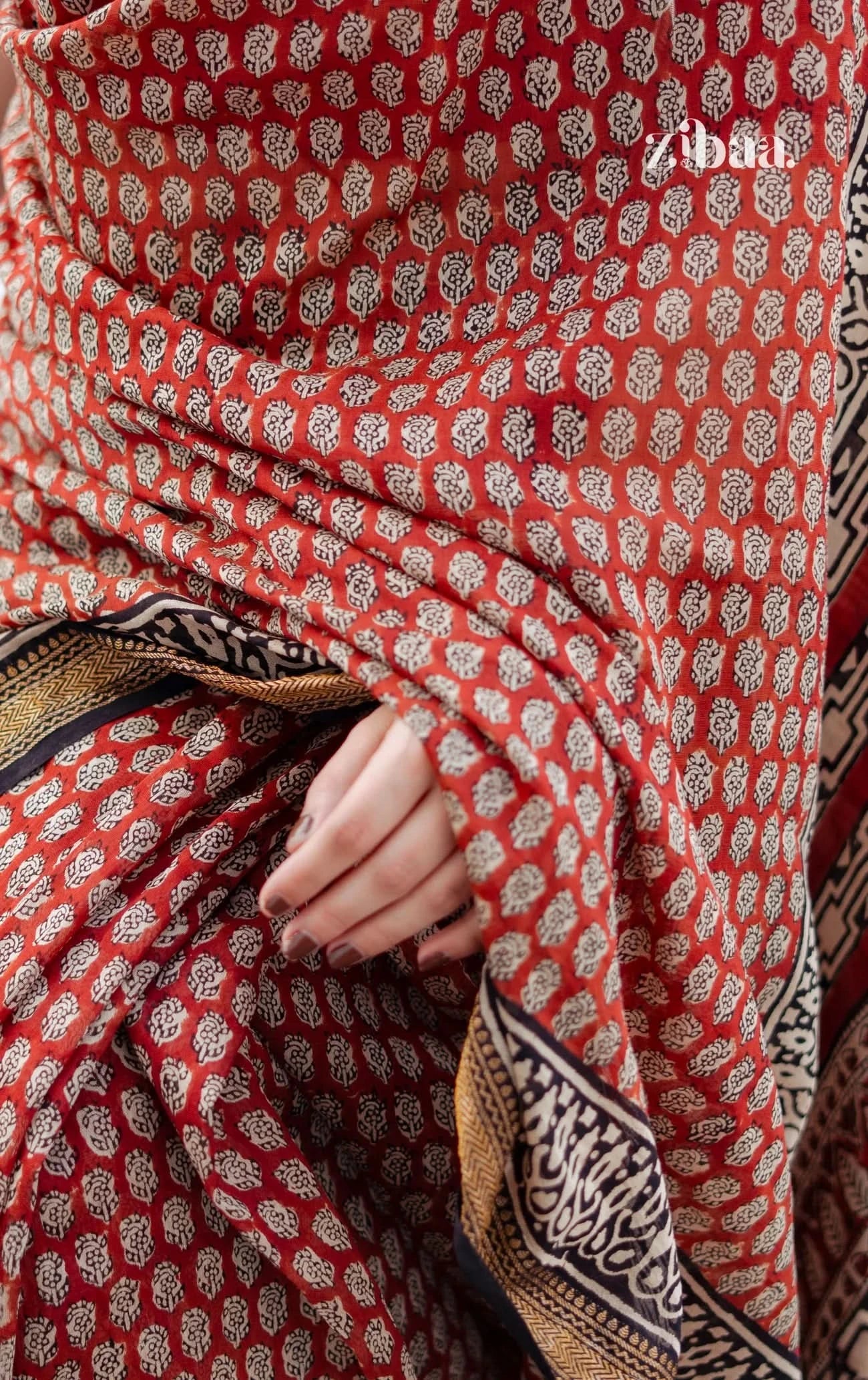 Close-up of a red patterned fabric with a hand holding it