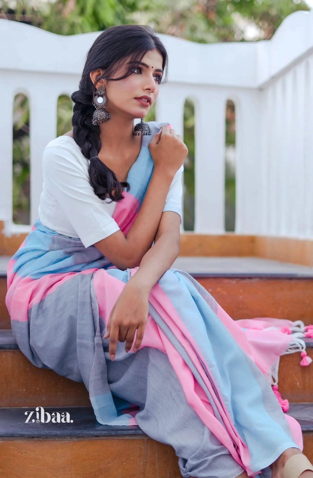 Woman in a traditional saree sitting on a bench with a blurred background
