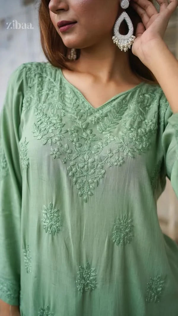 Woman wearing a green embroidered dress with a blurred background
