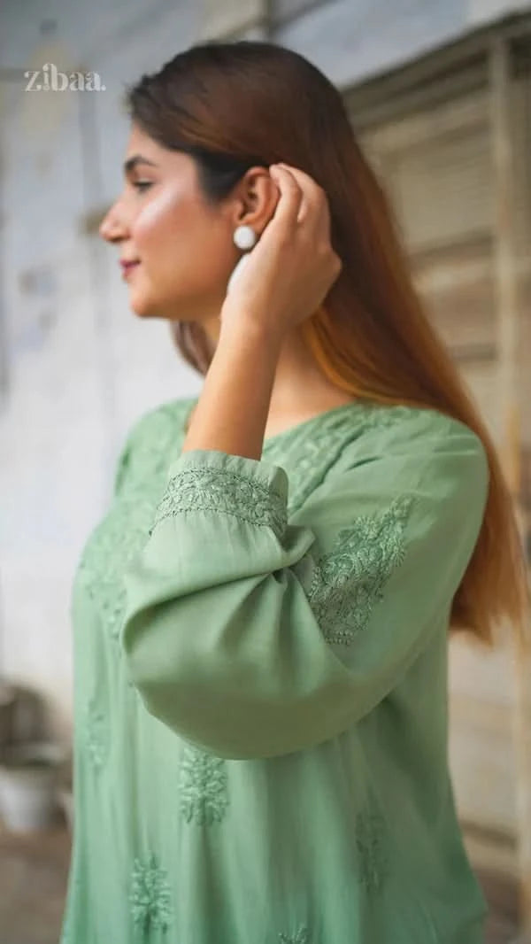 Woman wearing a green embroidered blouse with a blurred background