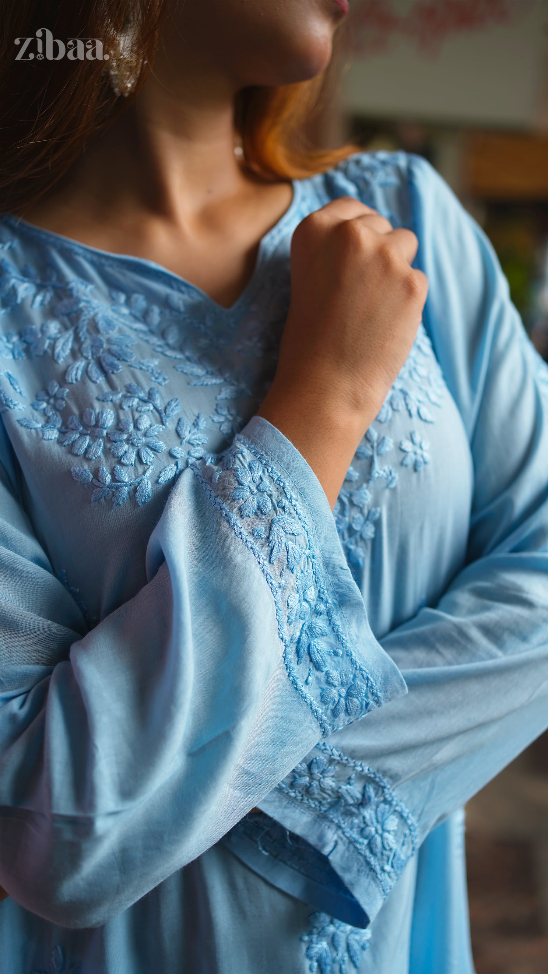 Close-up of a person wearing a light blue chikankari kurti with intricate details.