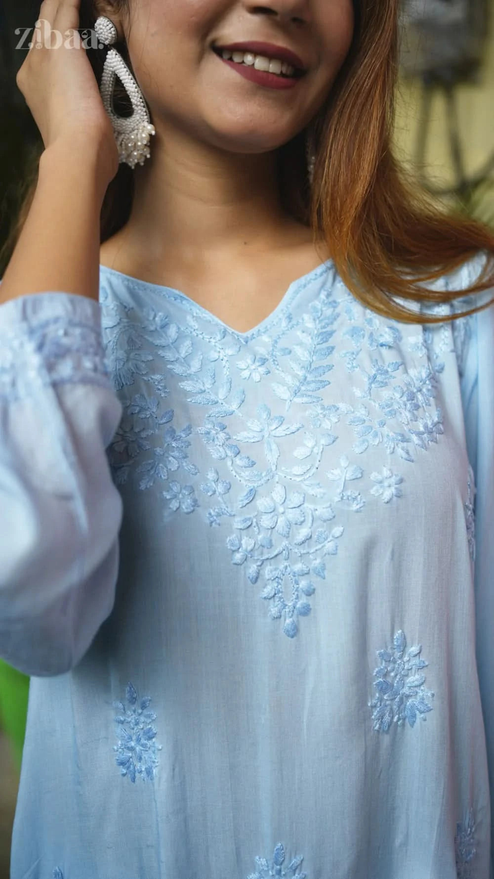 Light blue embroidered top worn by a person, with a blurred background