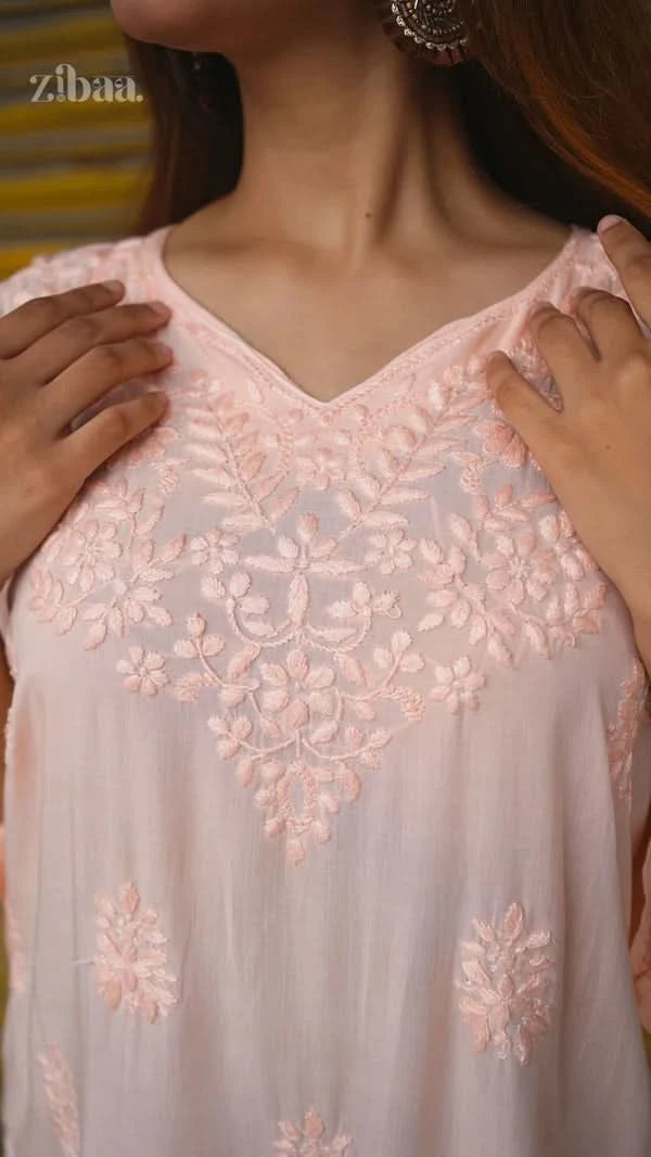 Close-up of a light pink embroidered dress with floral patterns.