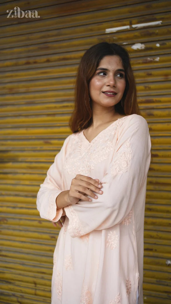 Woman in a light pink dress standing in front of a yellow shutter.
