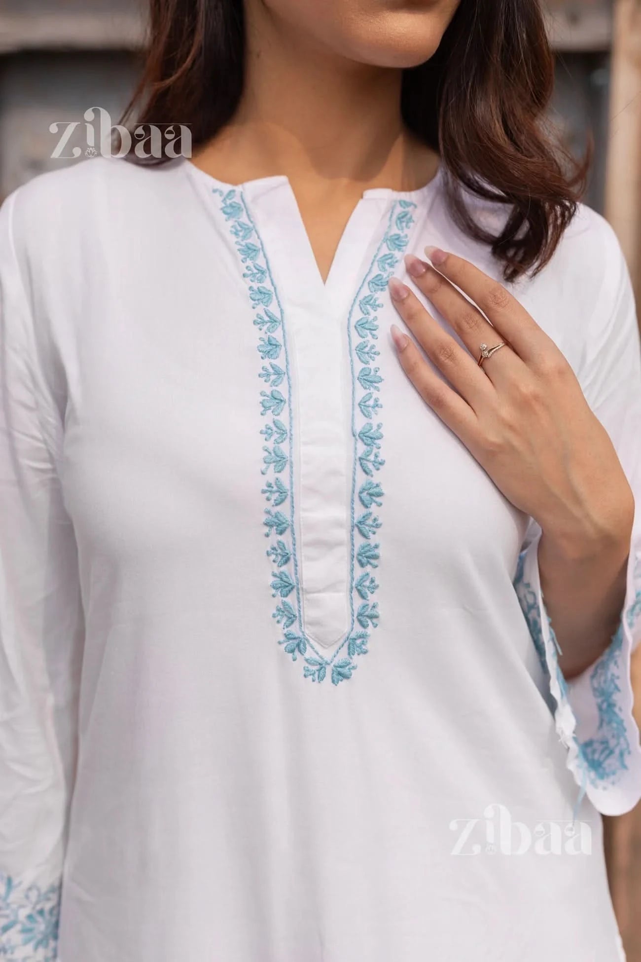 White top with blue embroidery on a neutral background, featuring the brand 'zibaa'.