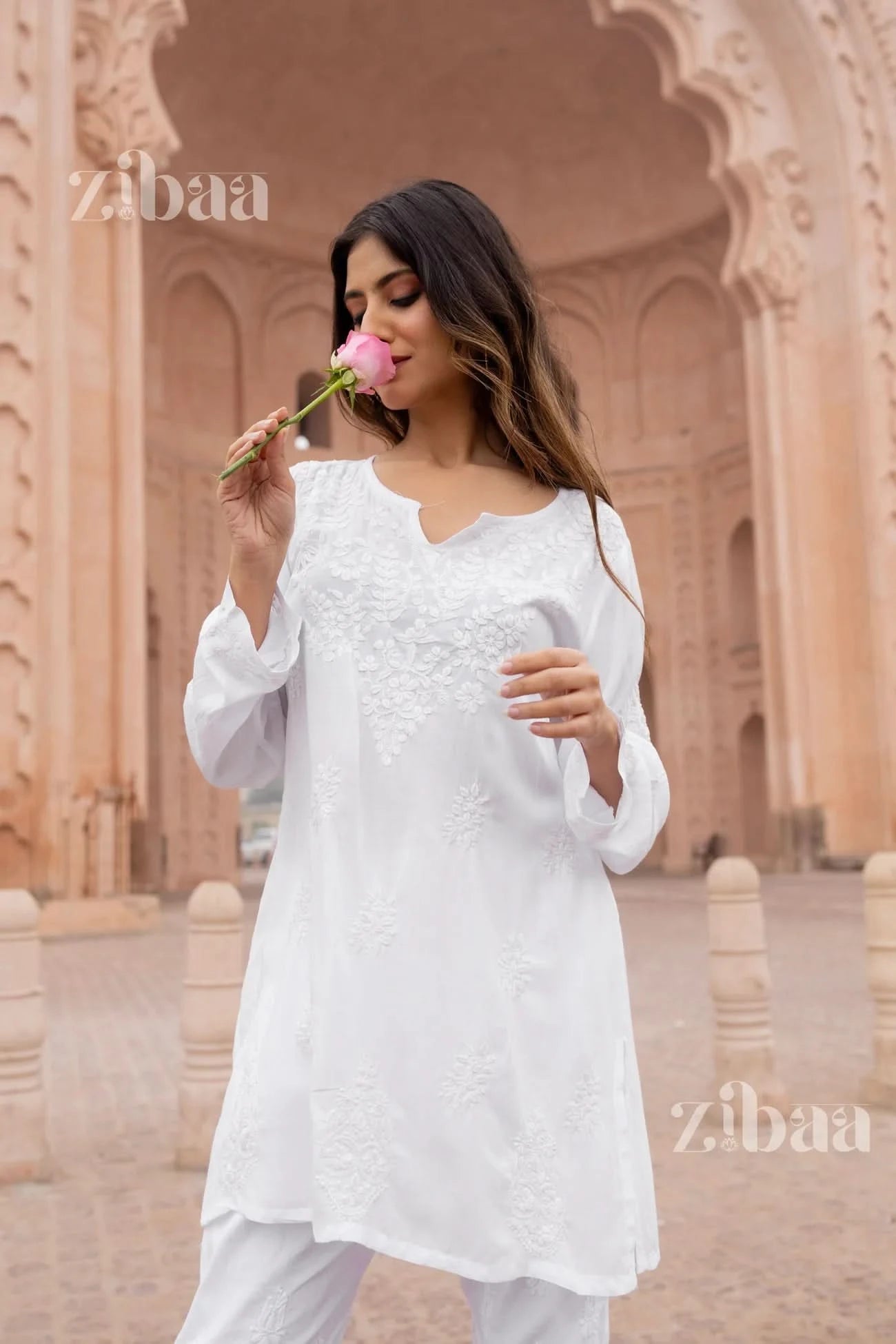 Woman wearing a white short chikankari kurti standing outdoors.