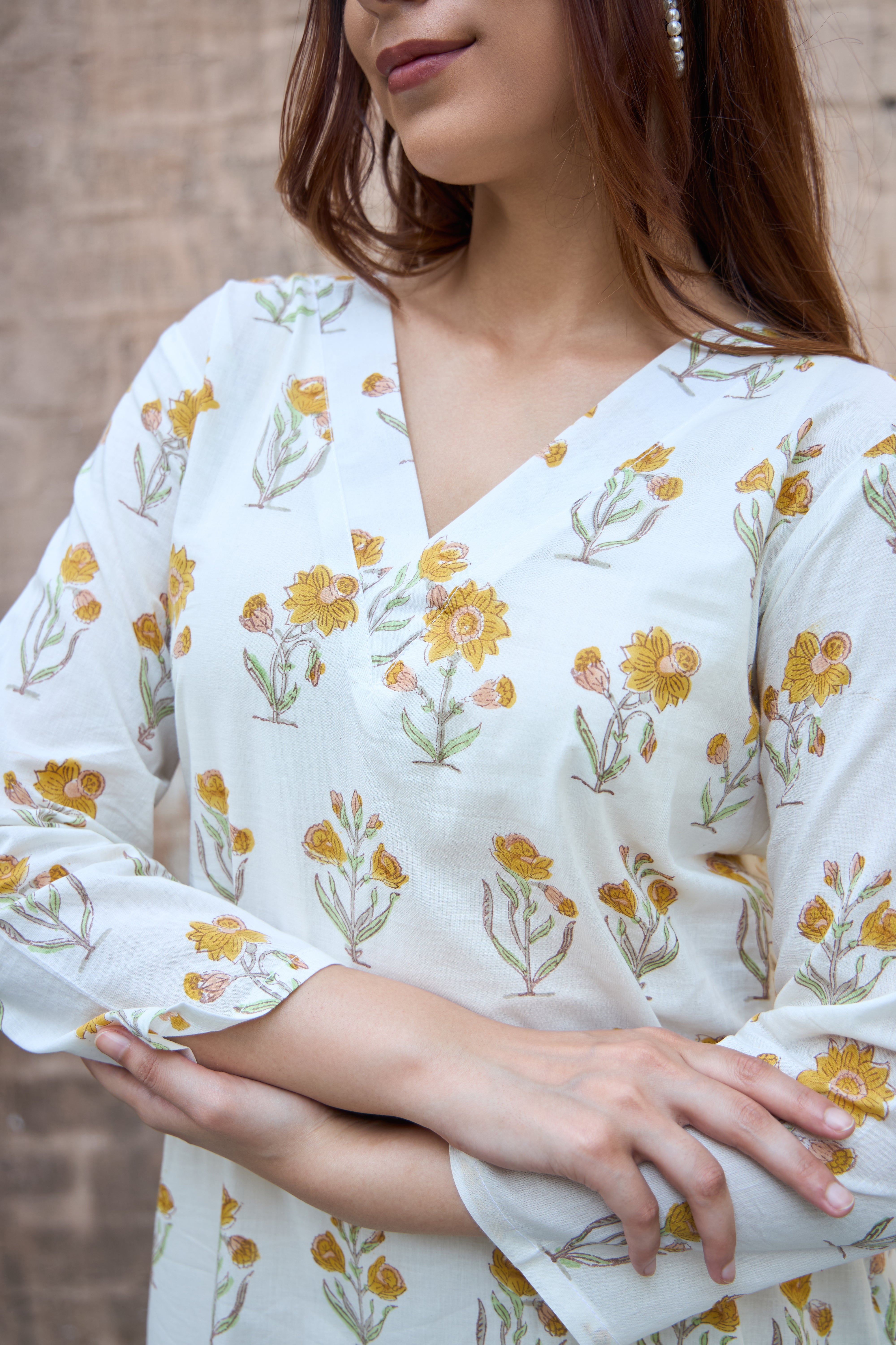 Woman wearing a white floral blouse with yellow flowers against a blurred background