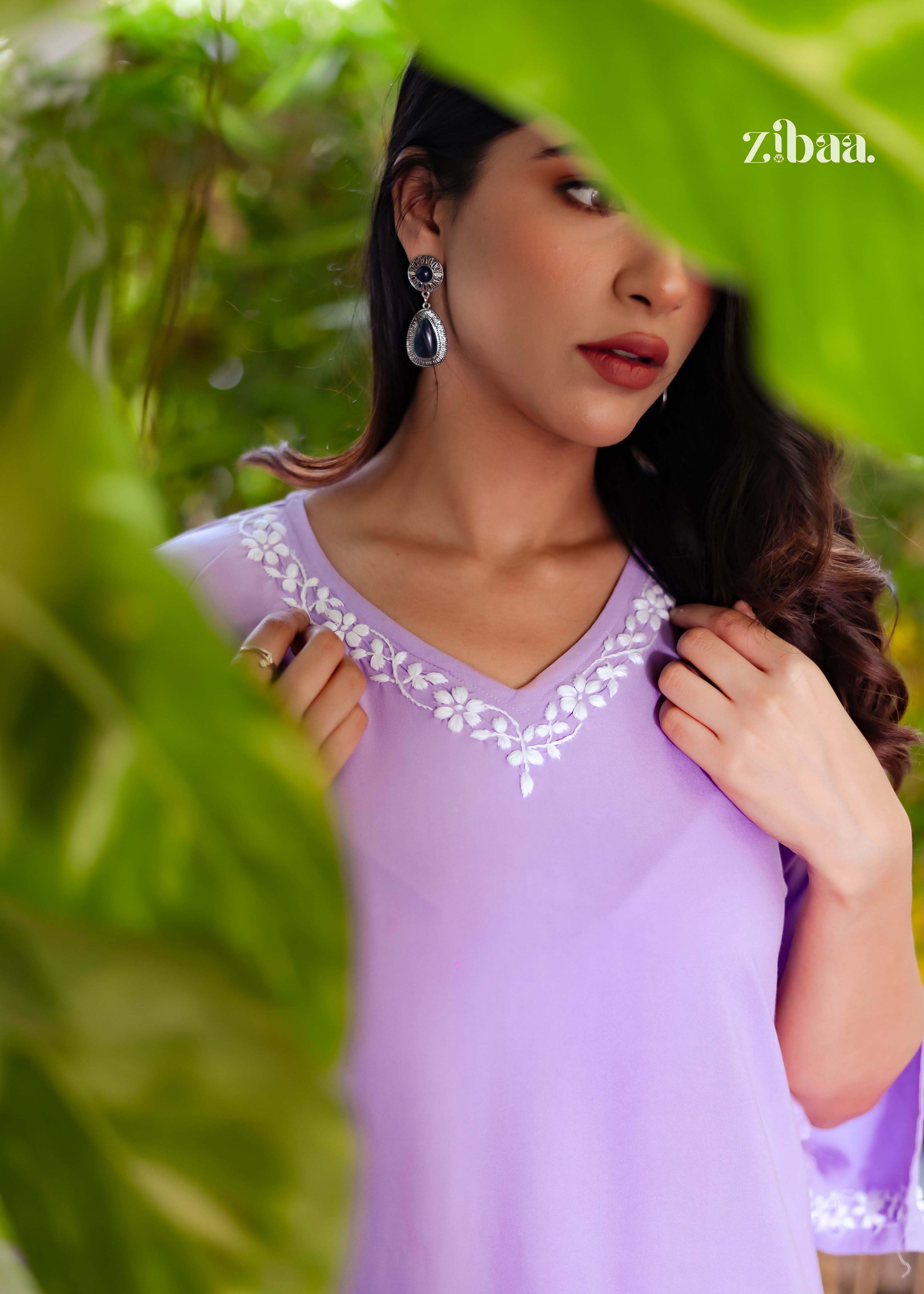 Standing in an open outdoor setting, the model showcases a lavender chikankari kurti, drawing attention to the delicate embroidery along the neckline.