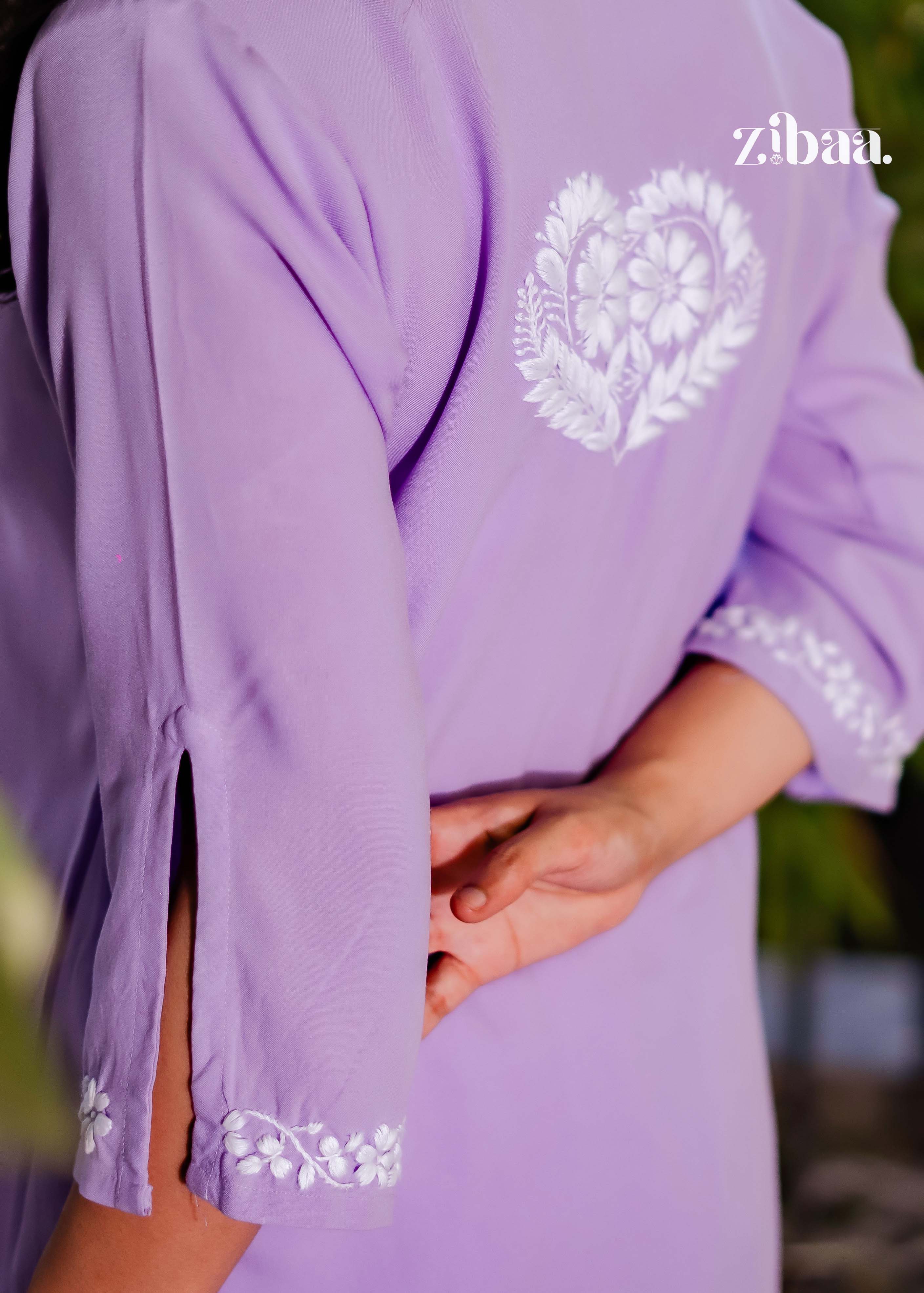 The backshot captures the fine embroidery on the lavender chikankari kurti as the model faces away in a calm outdoor scene.
