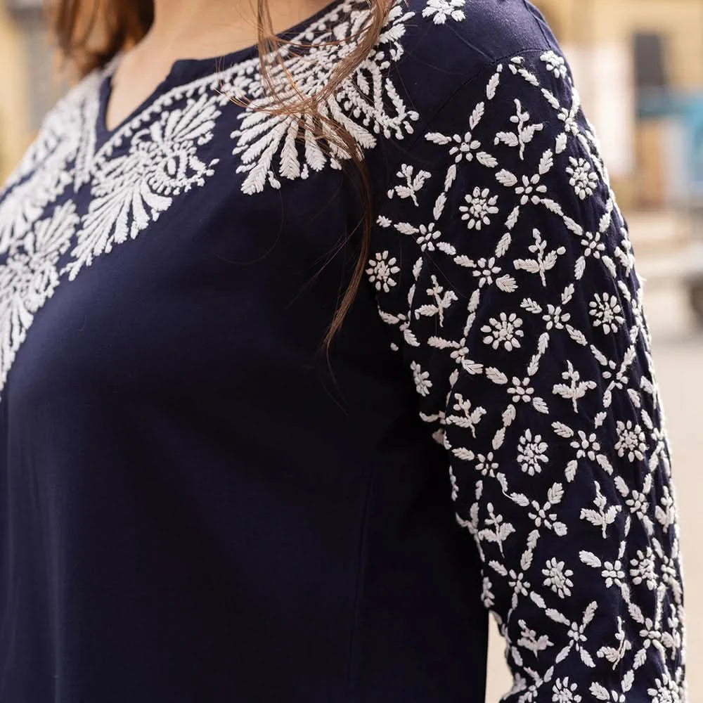 Navy blue top with white floral embroidery on a blurred background