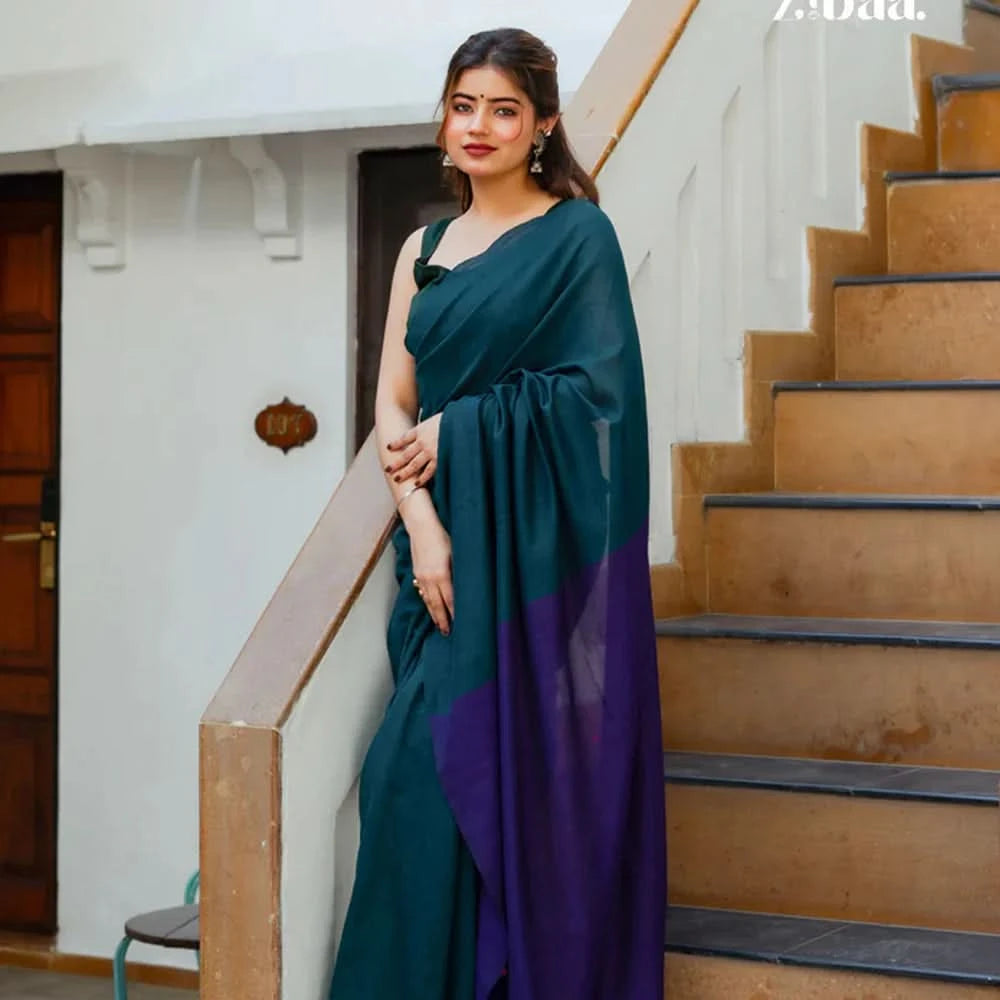 Woman in a green and purple saree standing on a staircase