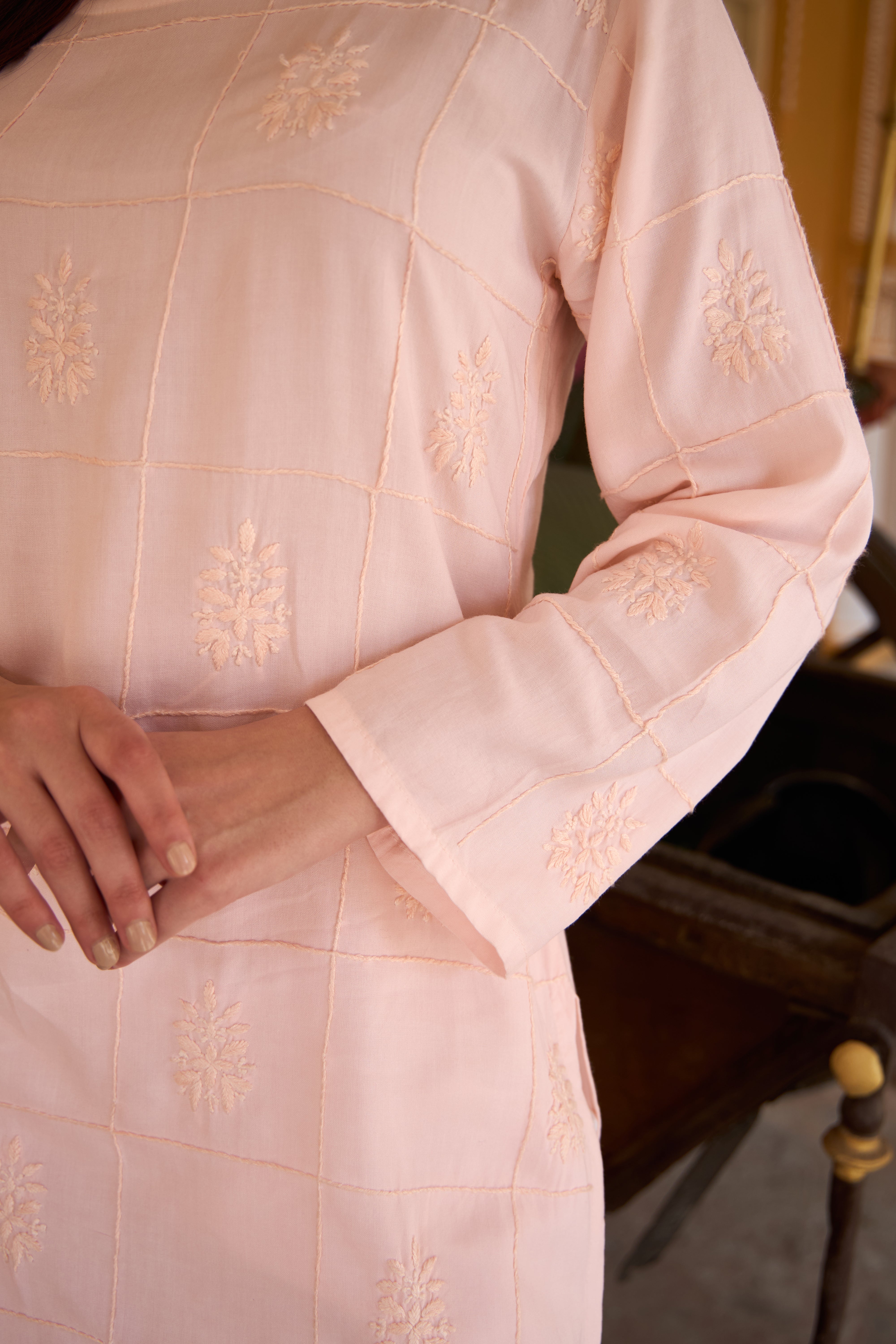 Close-up of a light pink traditional outfit with intricate gold embroidery.