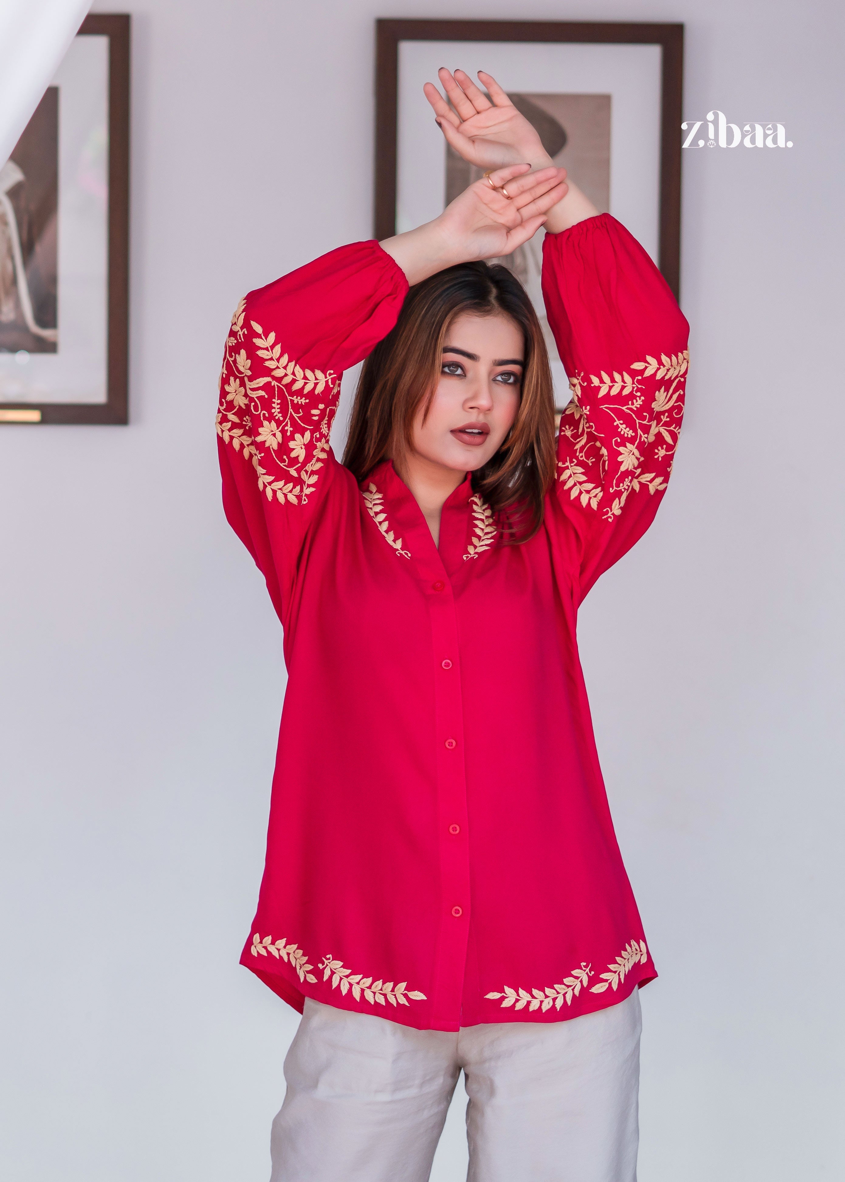 The model poses with raised arms in a Pink Kurta with Golden Leaf Embroidery. Bright Pink Kurta with Golden Leaf Embroidery enhances traditional style with modern comfort. The soft beige pants balance the vibrant top.