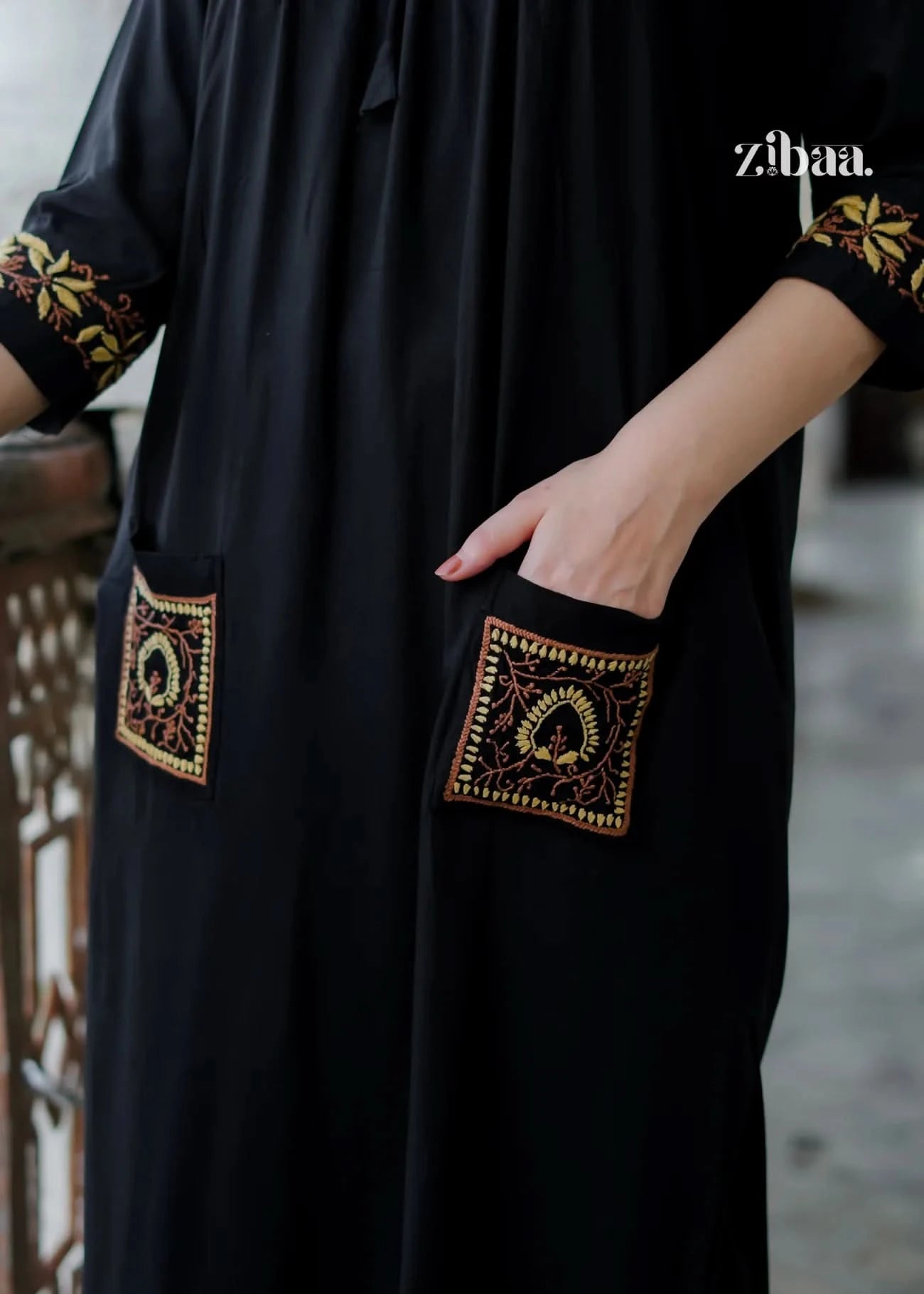 A close-up reveals the rich golden embroidery on the pockets and cuffs of the black chikankari kurti, bringing the delicate design and texture into focus.