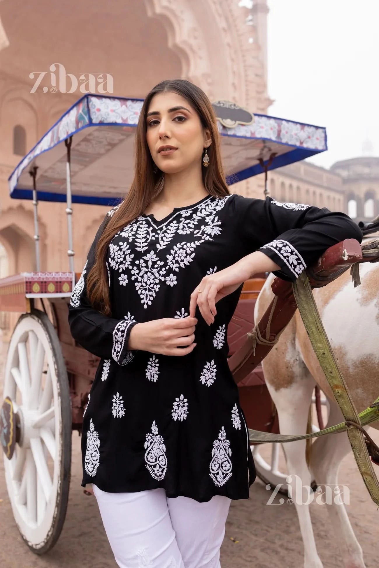 Black short chikankari kurti on woman with a traditional rickshaw in the background