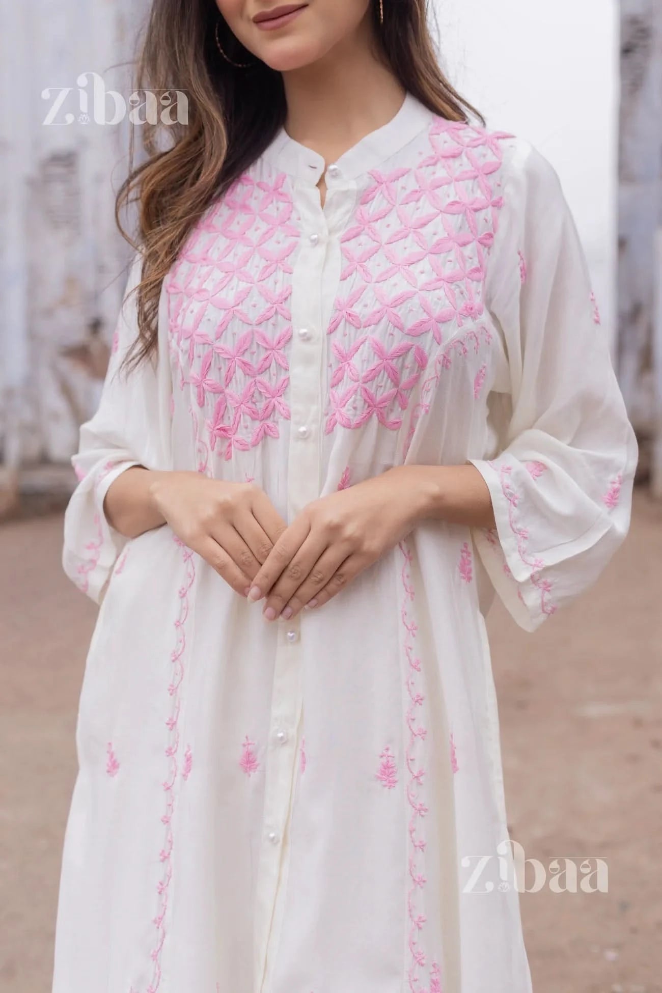 Woman in a traditional yet trendy white chikankari kurta with pink embroidery, photographed outdoors