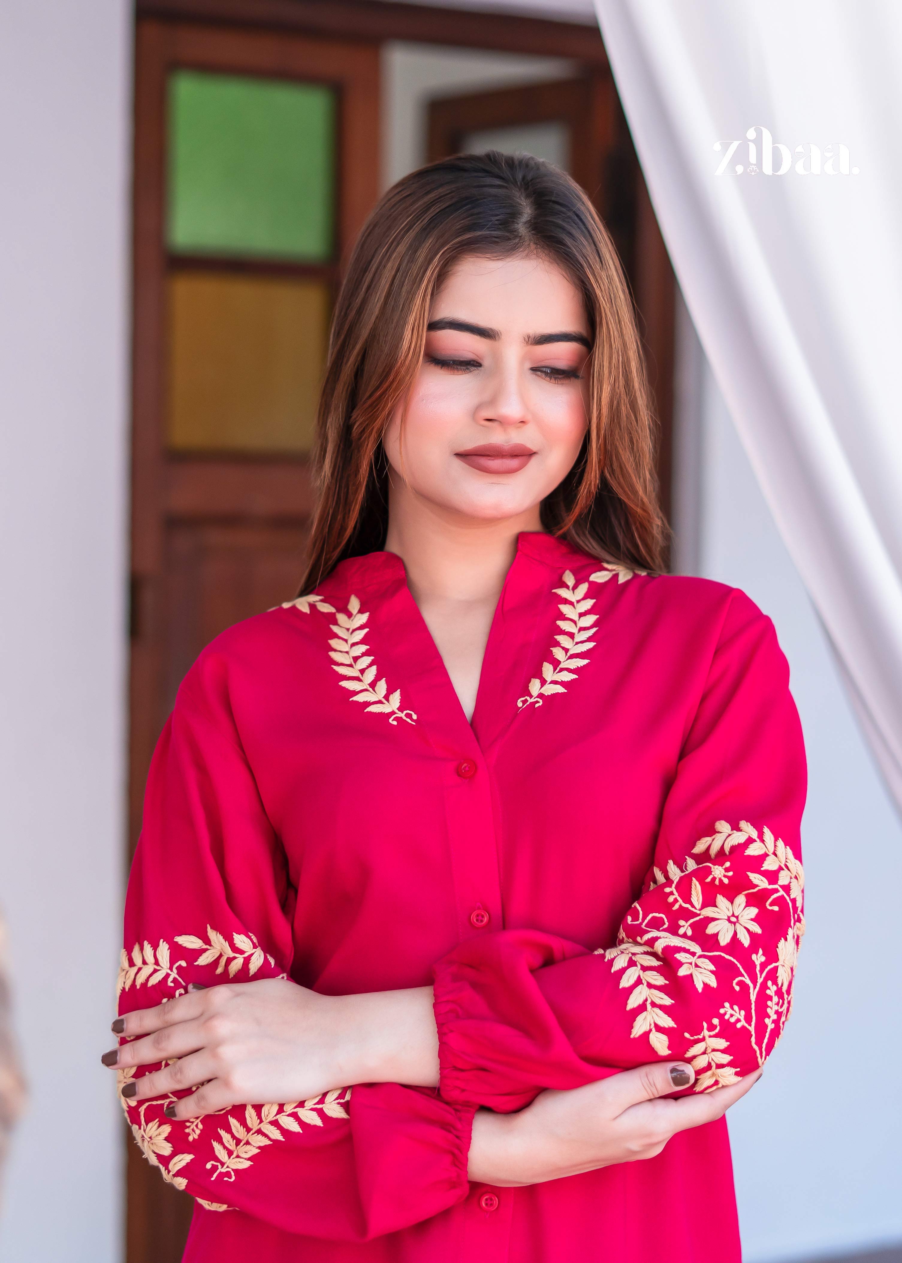 : The model sits gracefully wearing a Stylish Pink Kurta with Ethnic Embroidery. Stylish Pink Kurta with Ethnic Embroidery is paired with simple beige trousers. The soft backdrop draws focus to the vibrant outfit.