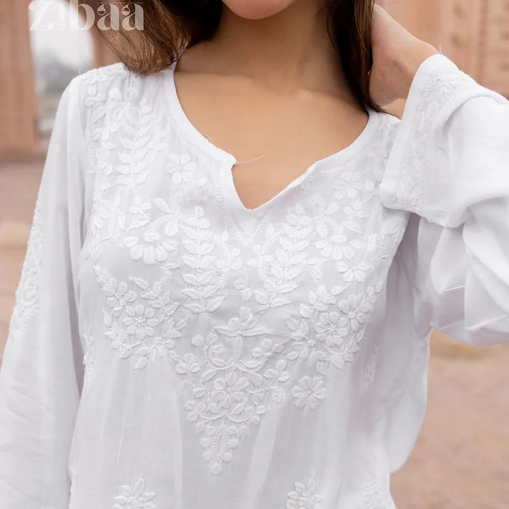White lace top worn by a person with a blurred background
