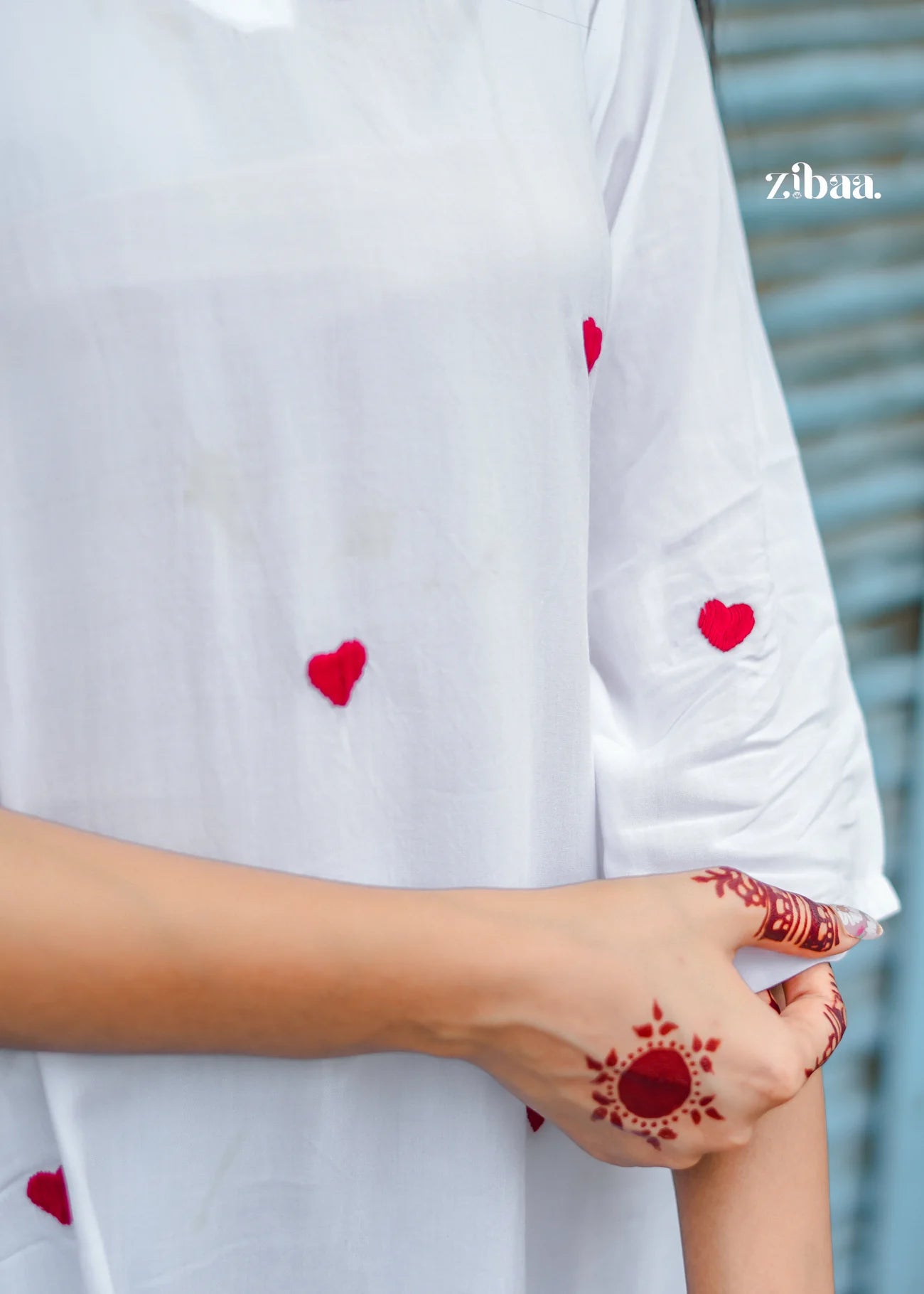 A close-up shot of the white chikankari kurti showcases the intricate red heart motifs and delicate embroidery, highlighting the fine craftsmanship.