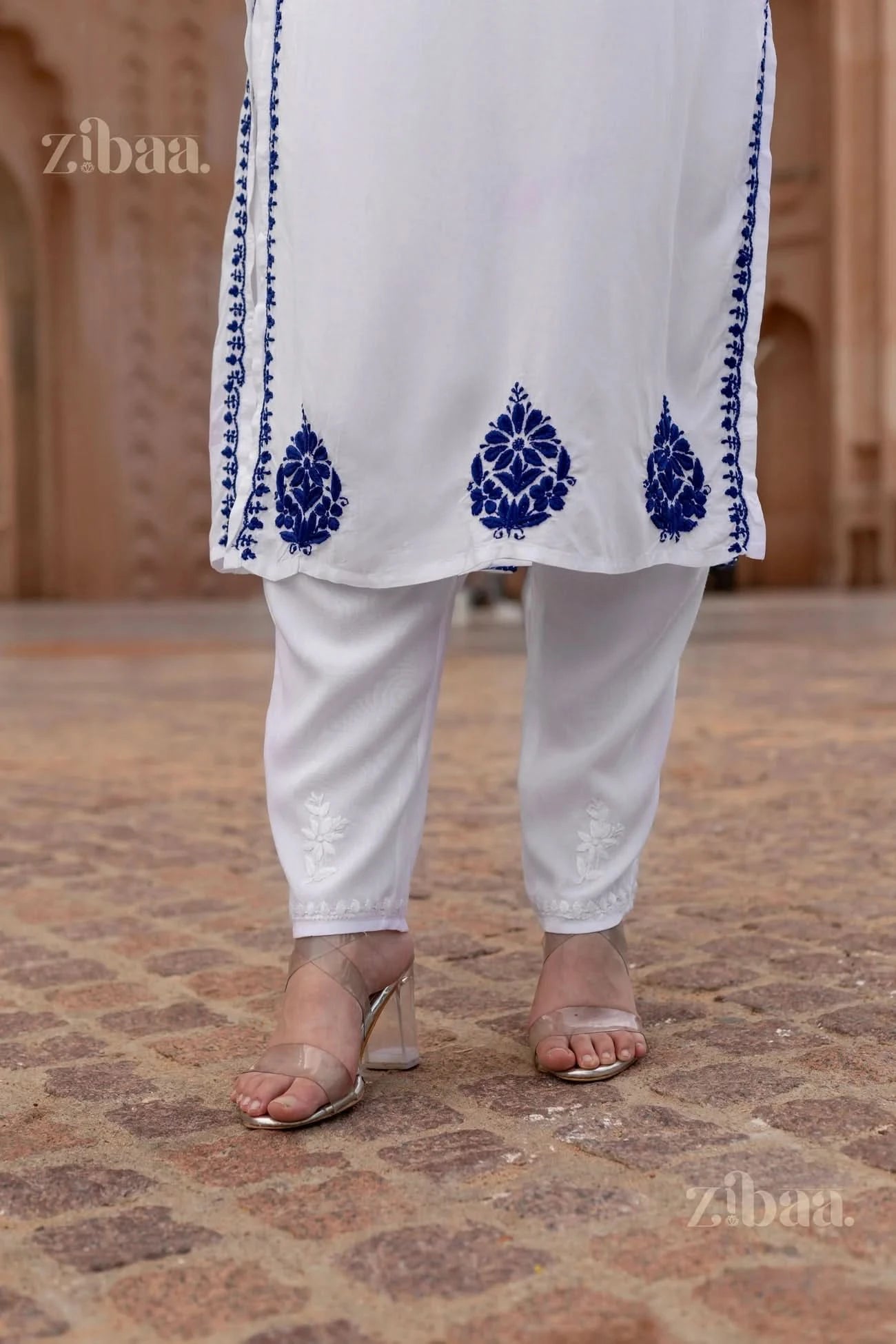 White outfit with blue embroidery on a patterned floor, brand 'zibaa' visible.