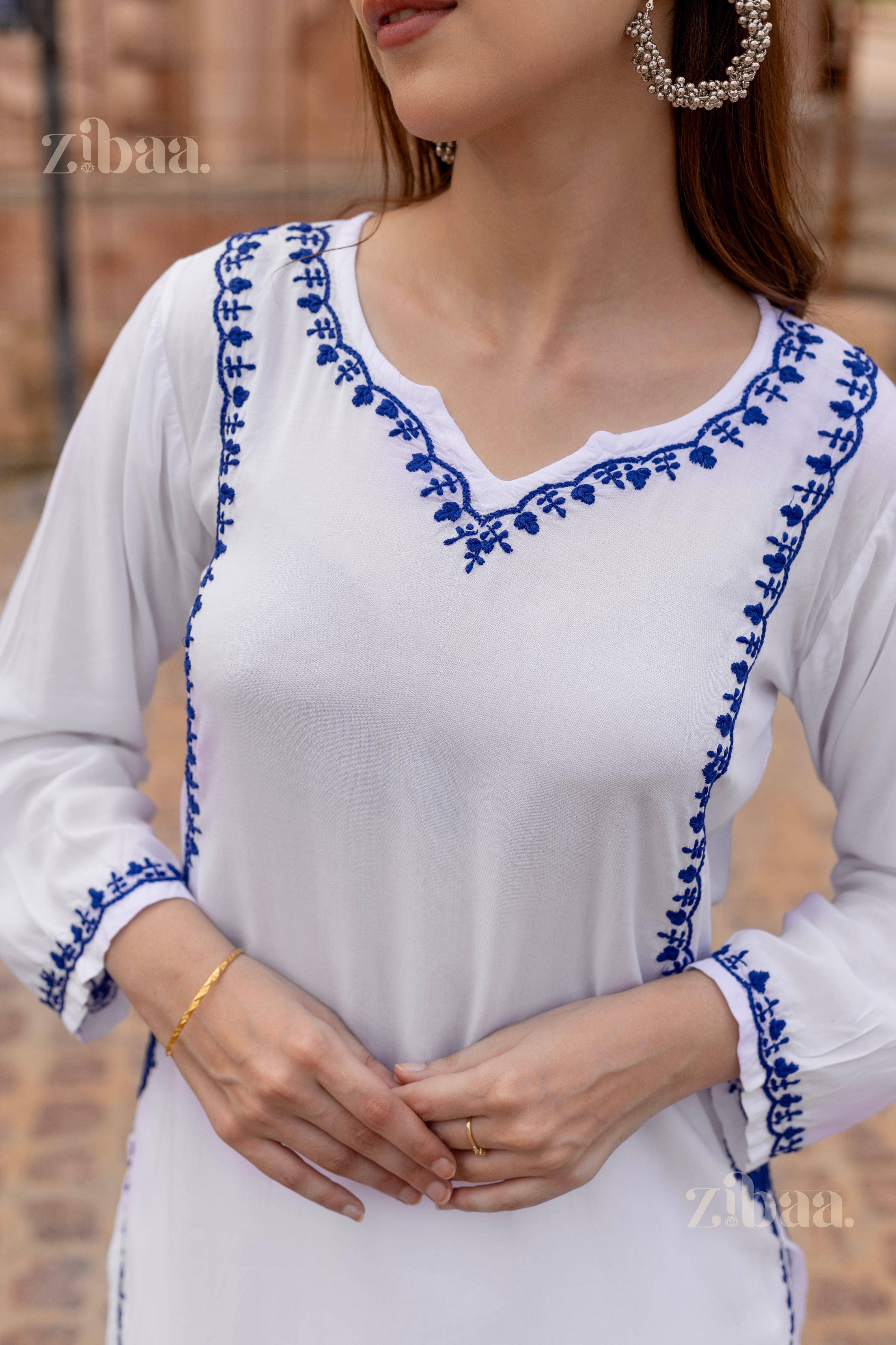 Close-up of a woman wearing a white chikankari kurti with fine blue embroidery on the neckline and on the sides of the kurti.
