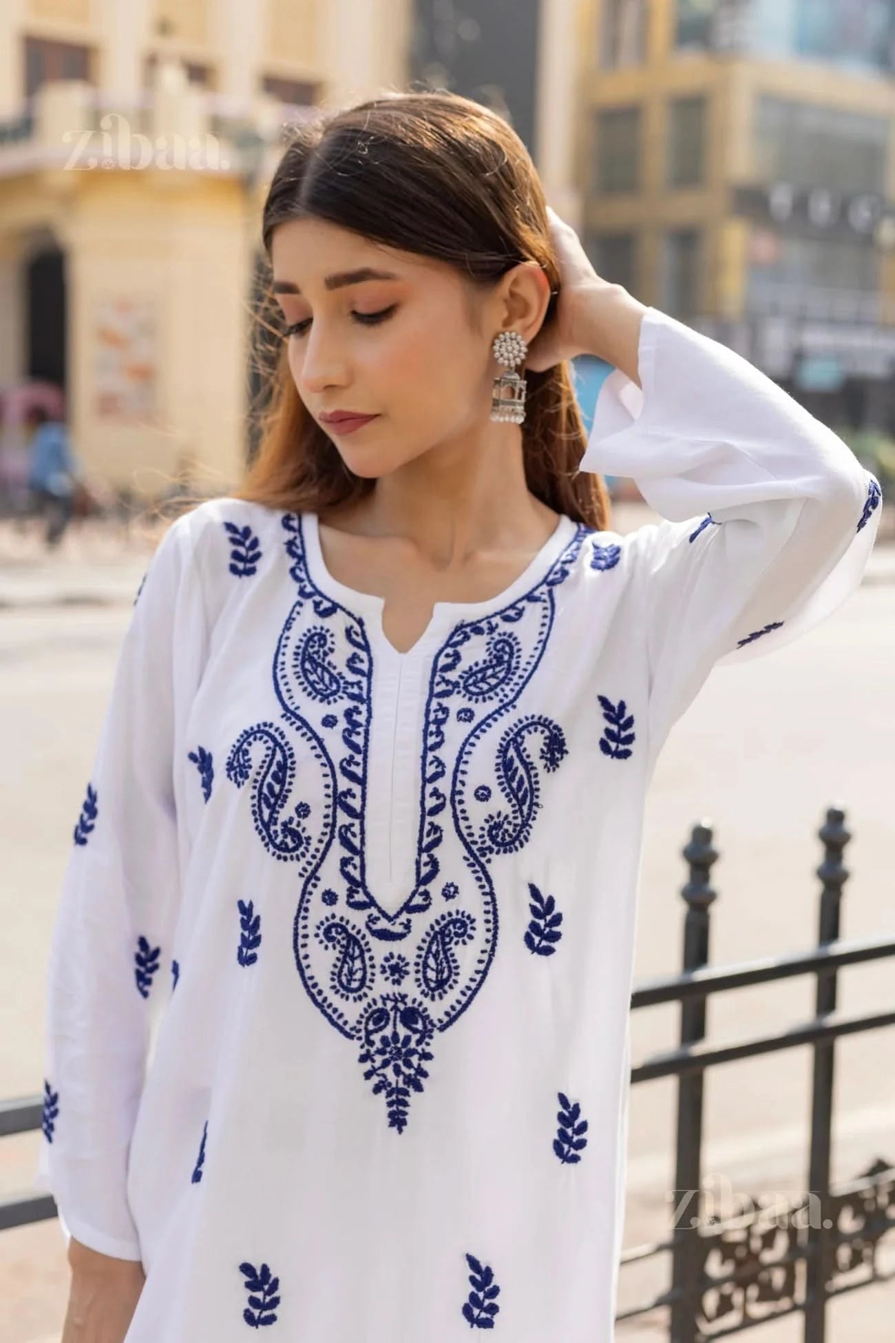 Close-up of a white Chikankari Kurti with intricate blue embroidery on the neckline and sleeves, blending history with modern style