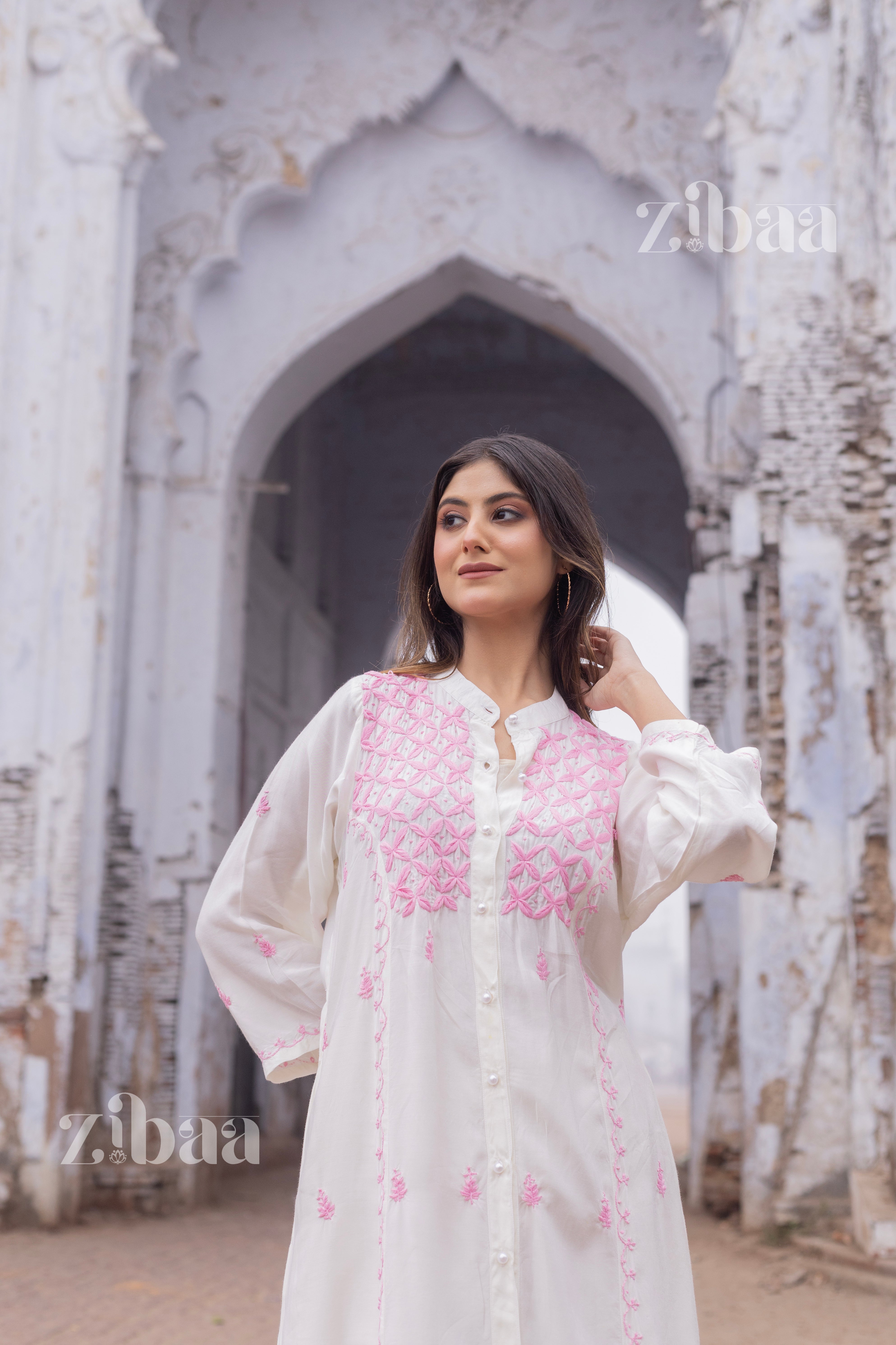 Long white chikankari kurta with pastel pink hand-embroidered details, captured in an outdoor setting.