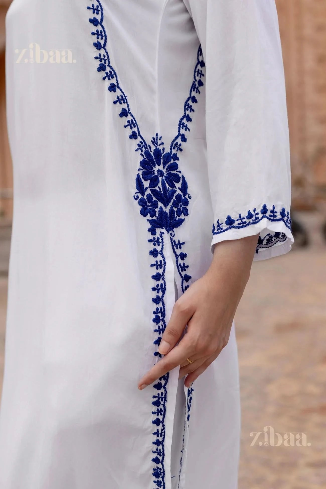 White garment with blue floral embroidery, brand 'zibma' visible