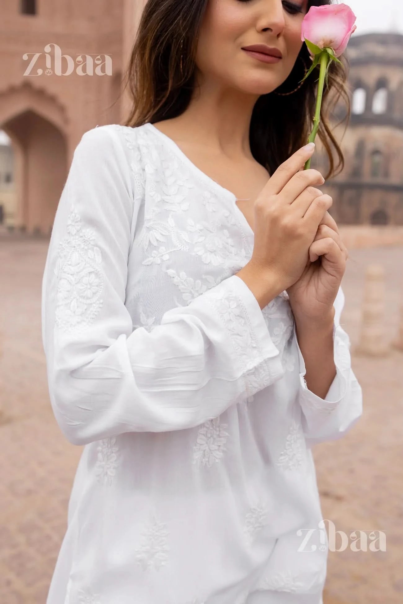Woman wearing a white short chikankari kurti standing outdoors.